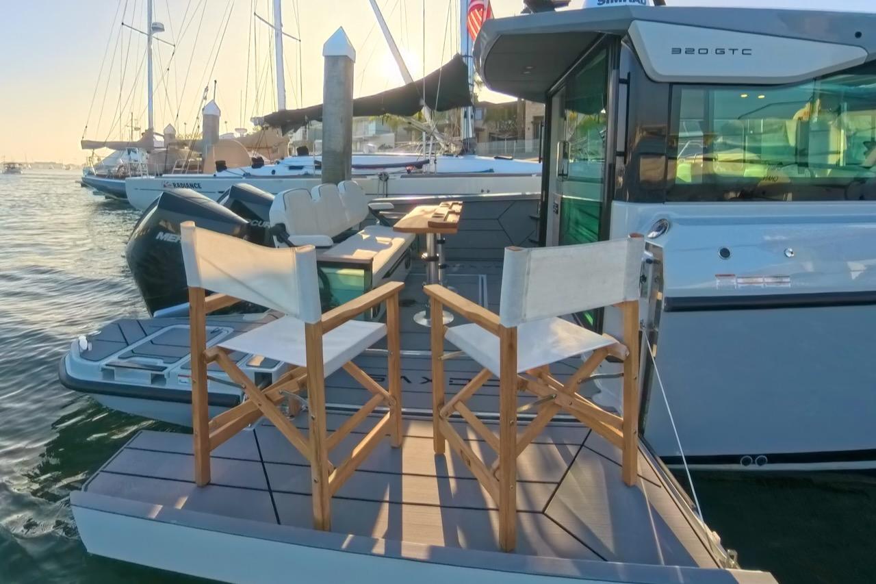 2024 Saxdor 320 GTC boat with deck chairs, docked in a marina at sunset.