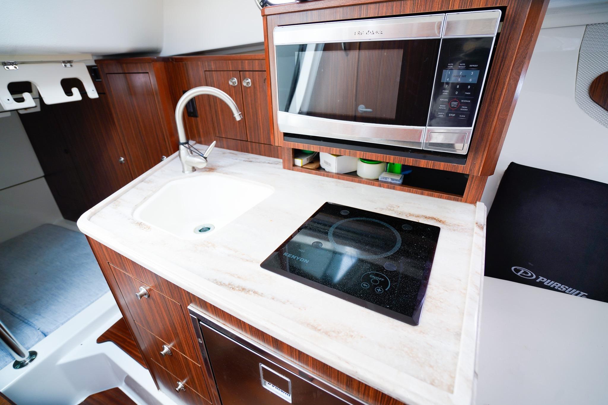 2020 Pursuit OS 325 Offshore yacht kitchen with sink, stove, and microwave.