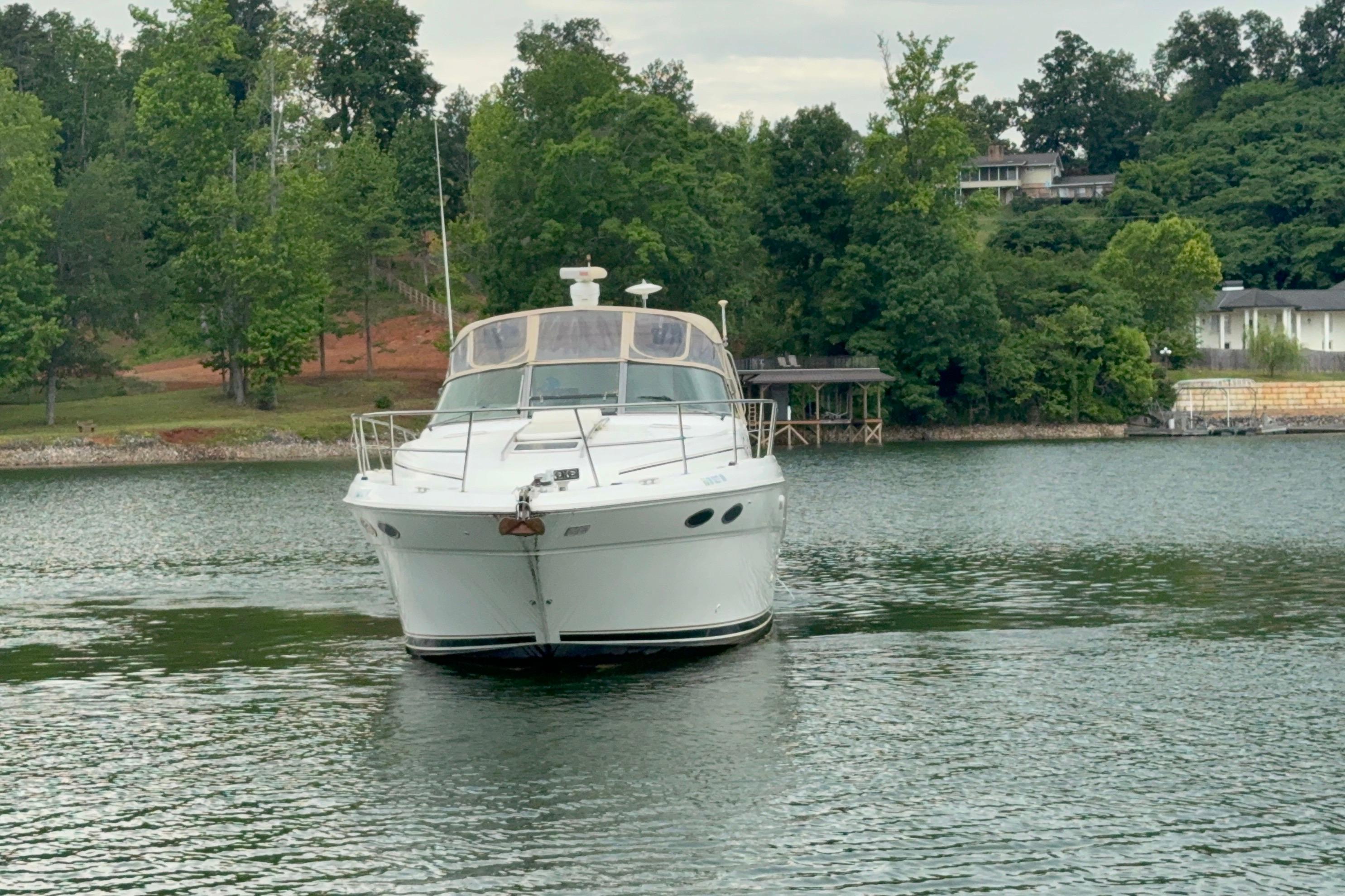 2001 Sea Ray 380 Sundancer yacht on a serene lake with lush green surroundings.