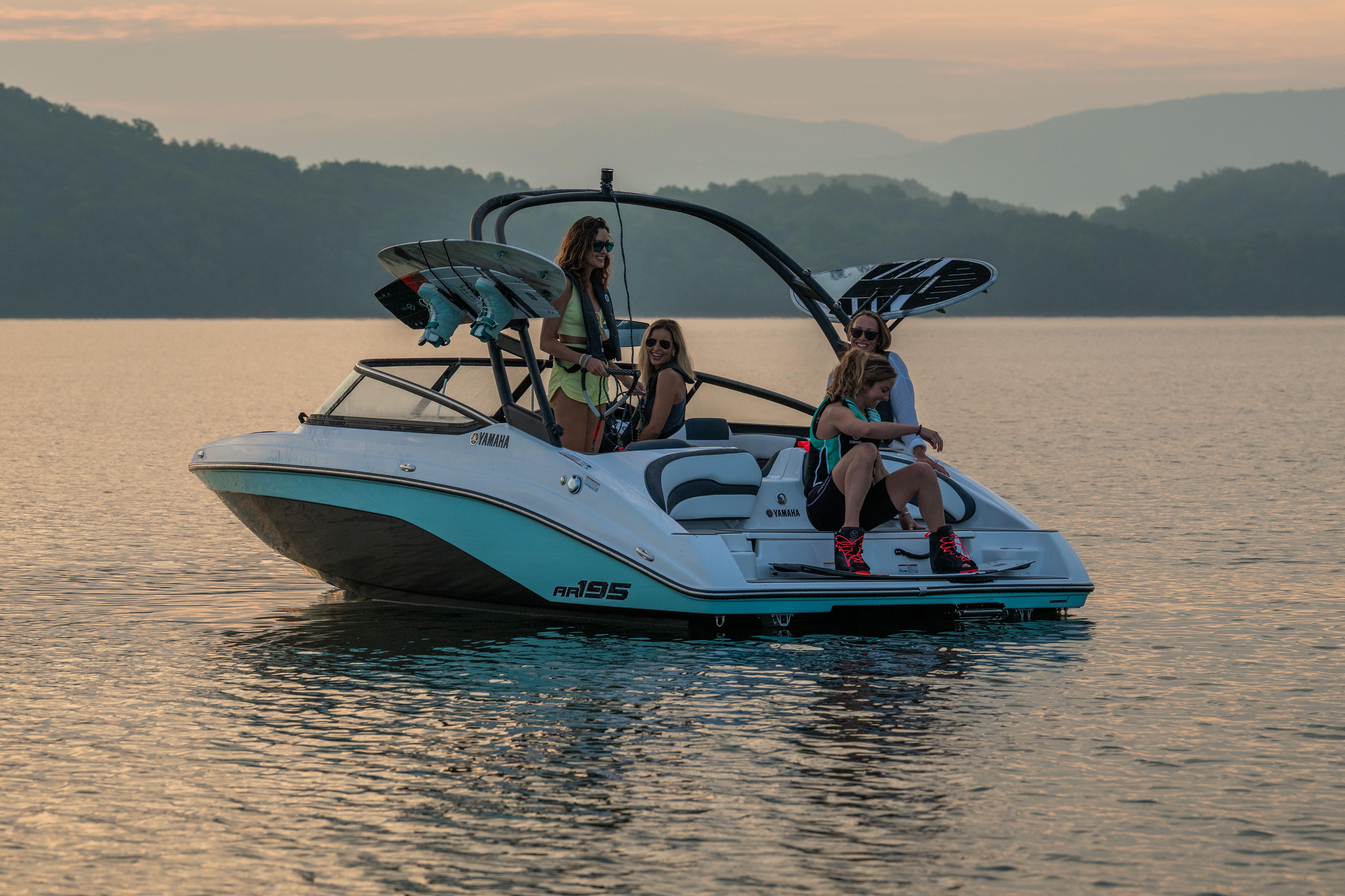 Manufacturer Provided Image: 2026 Yamaha AR195 boat with passengers enjoying a serene lake at sunset.