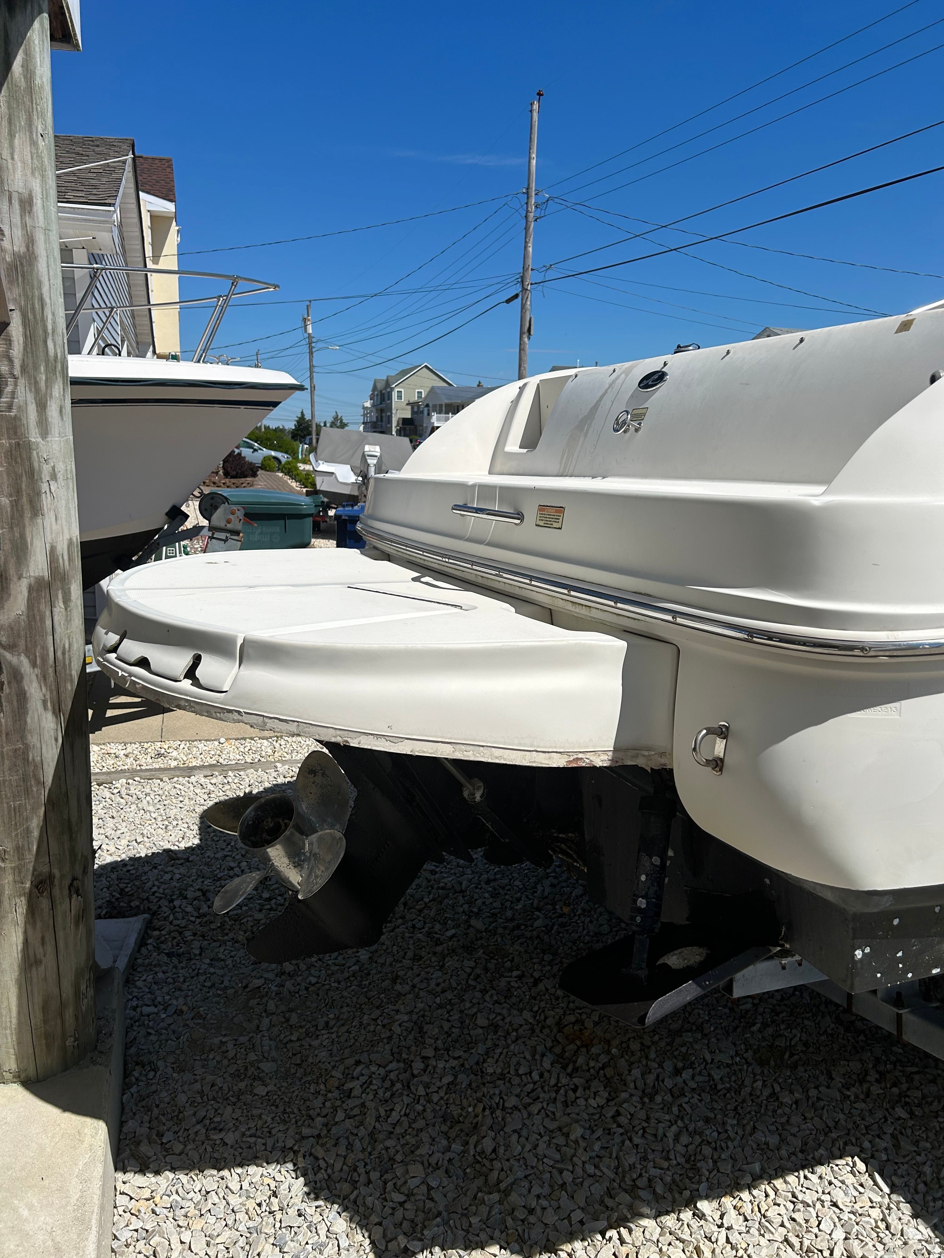 Rear view of a 2002 Sea Ray 225 Weekender on a gravel lot.