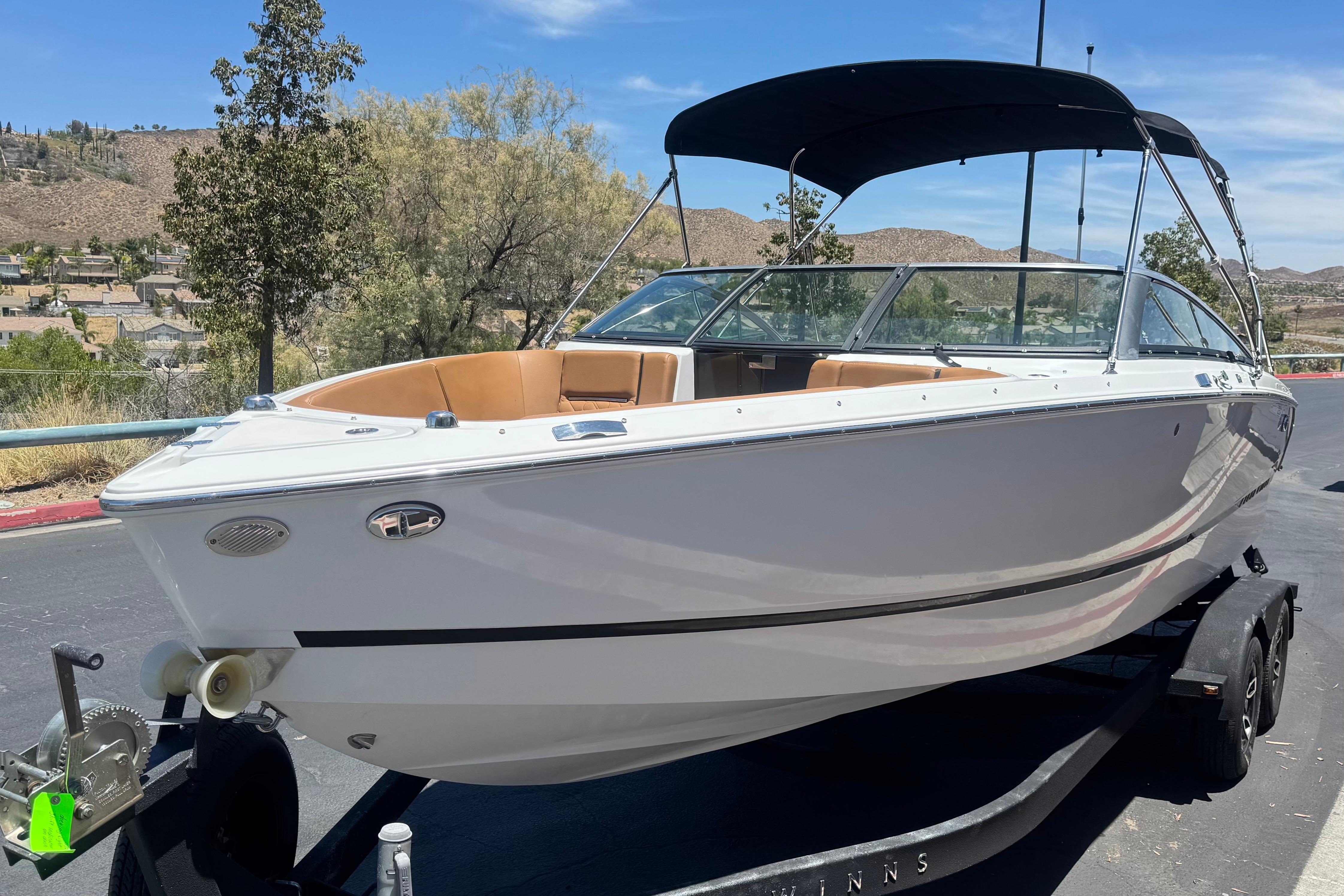 2022 Four Winns H4 boat on trailer, parked outdoors under clear blue sky.