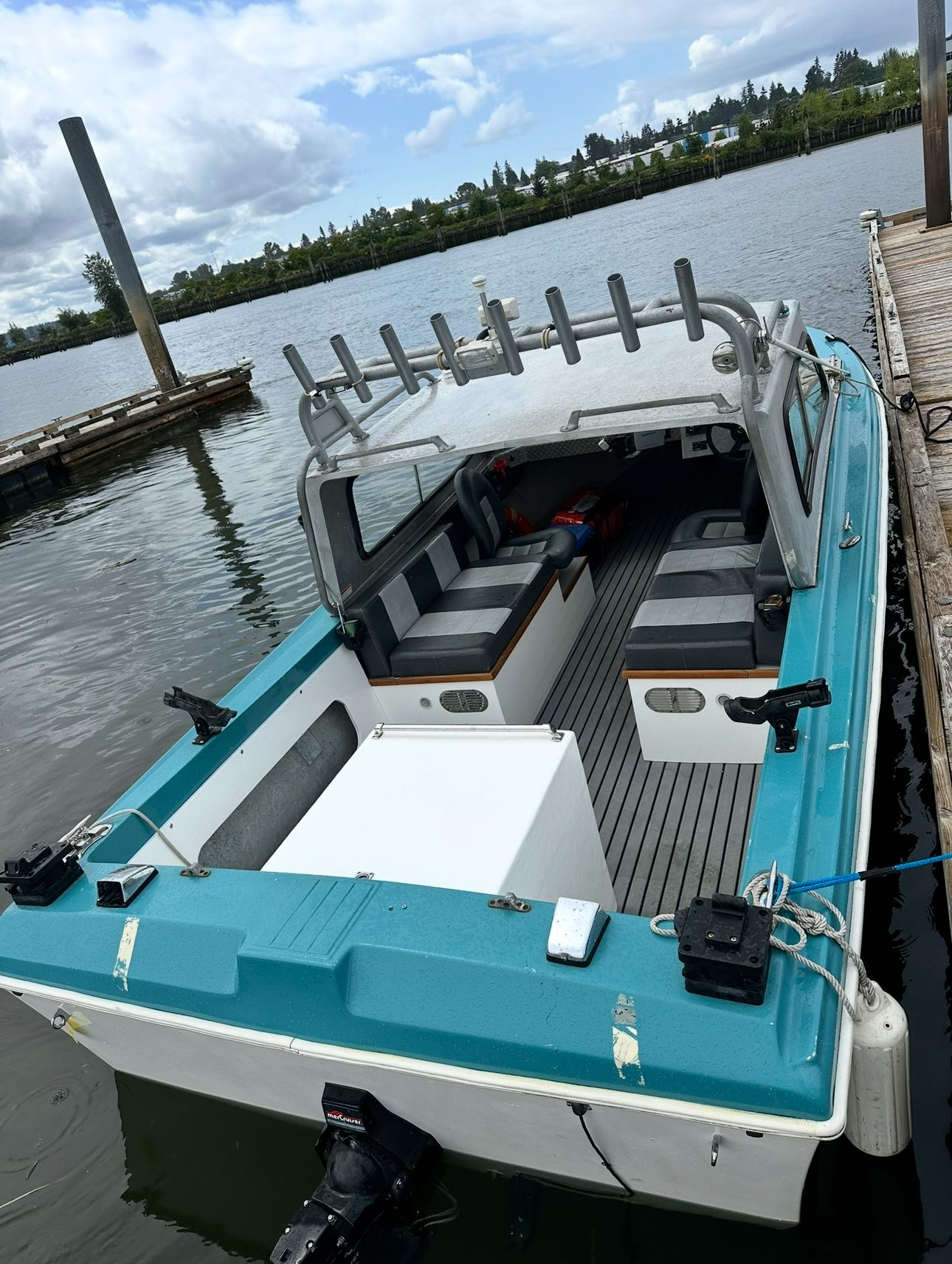 A restored 1967 Fiberform boat docked. It features a turquoise exterior and an open cabin.