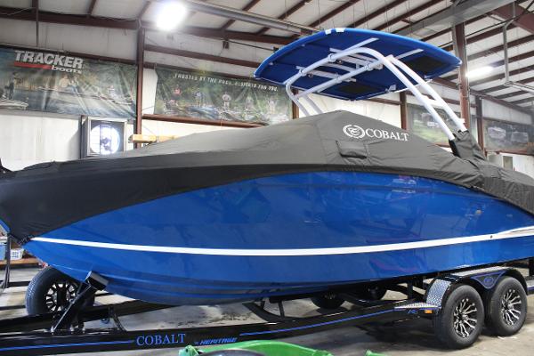 2025 Cobalt R6 boat in showroom, blue hull, black cover, on trailer.