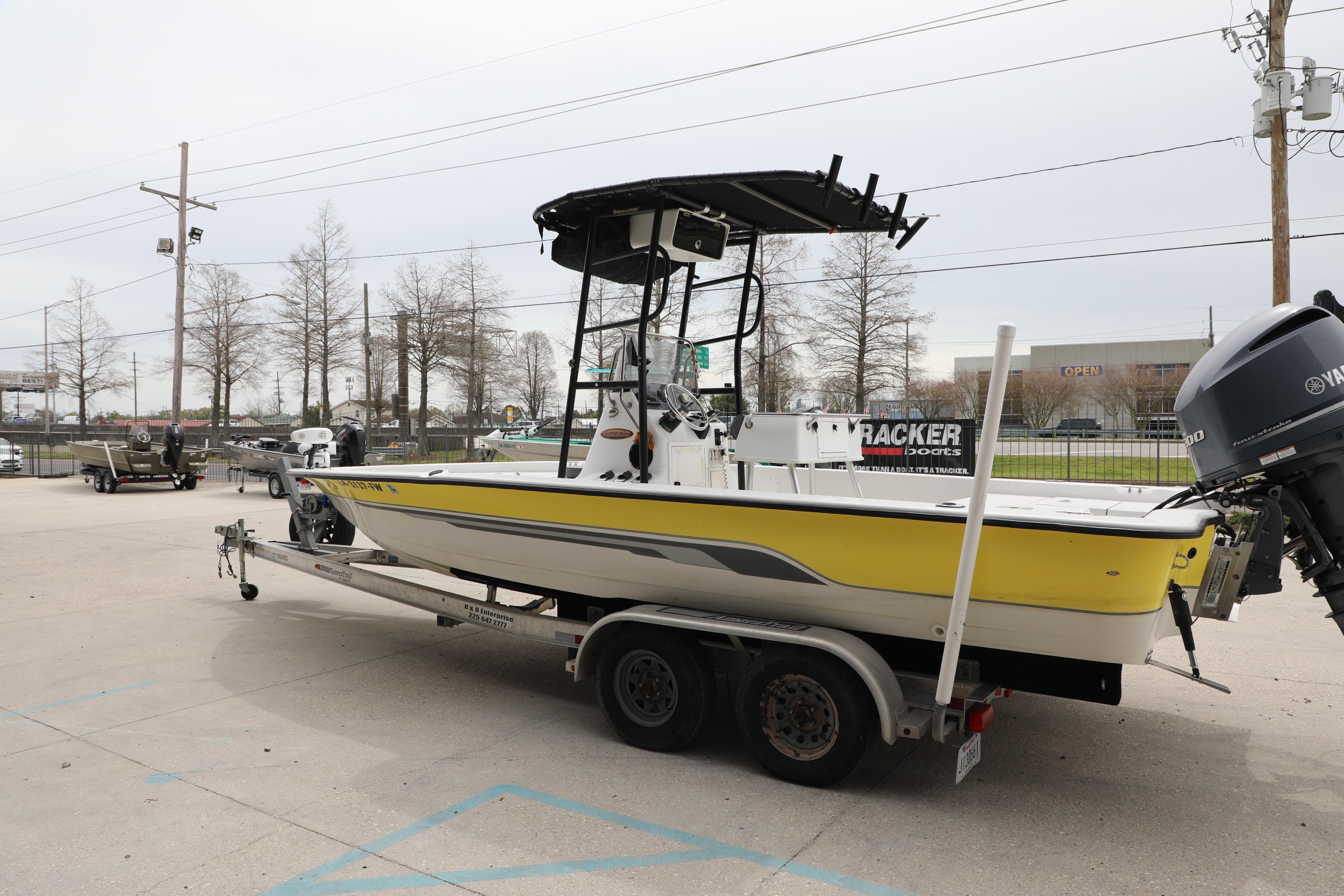 2002 Ranger 2300 Bay Ranger boat on trailer, yellow hull, parked outdoors.