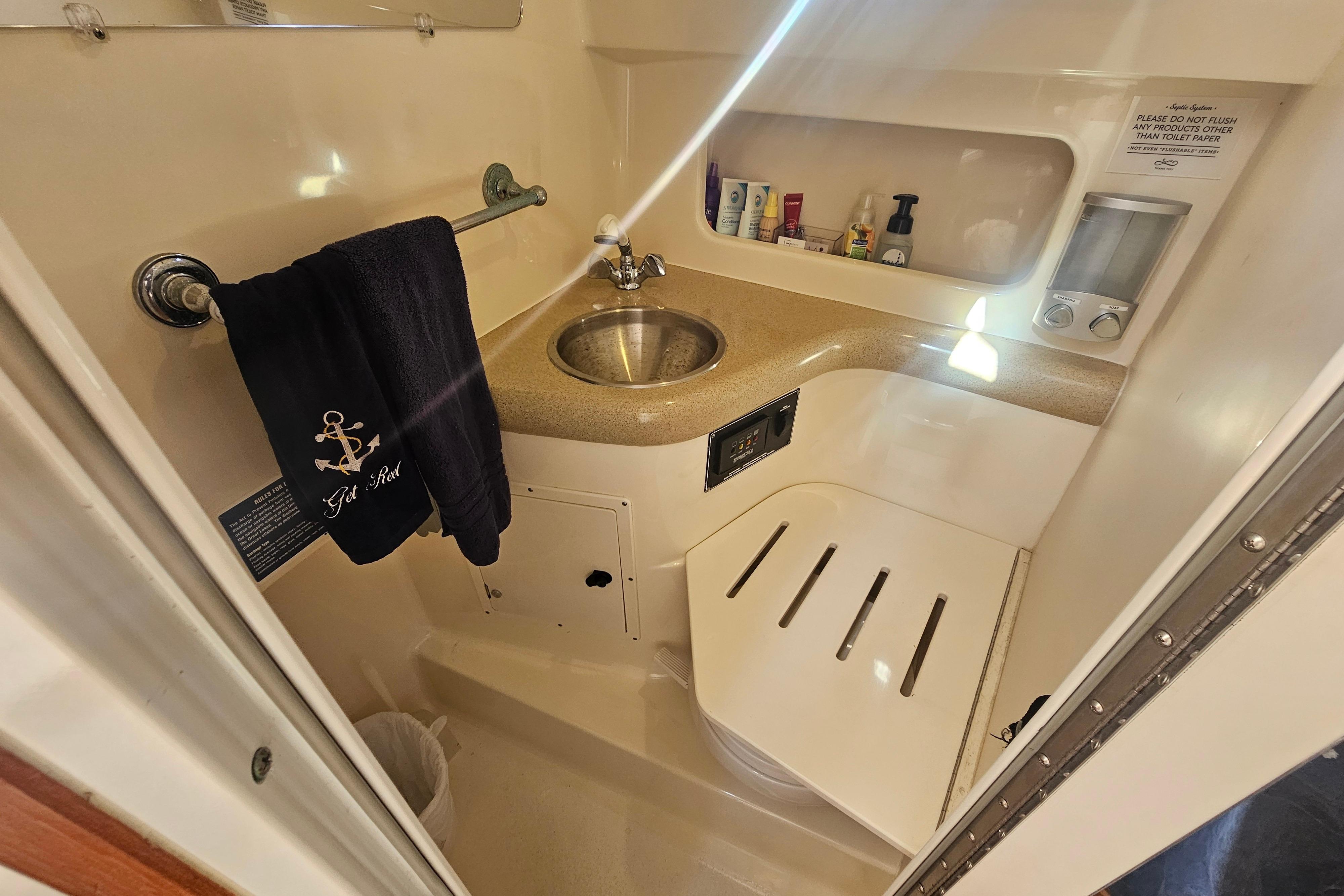2001 Pursuit 3000 Express boat bathroom with sink, towel, and toiletries.