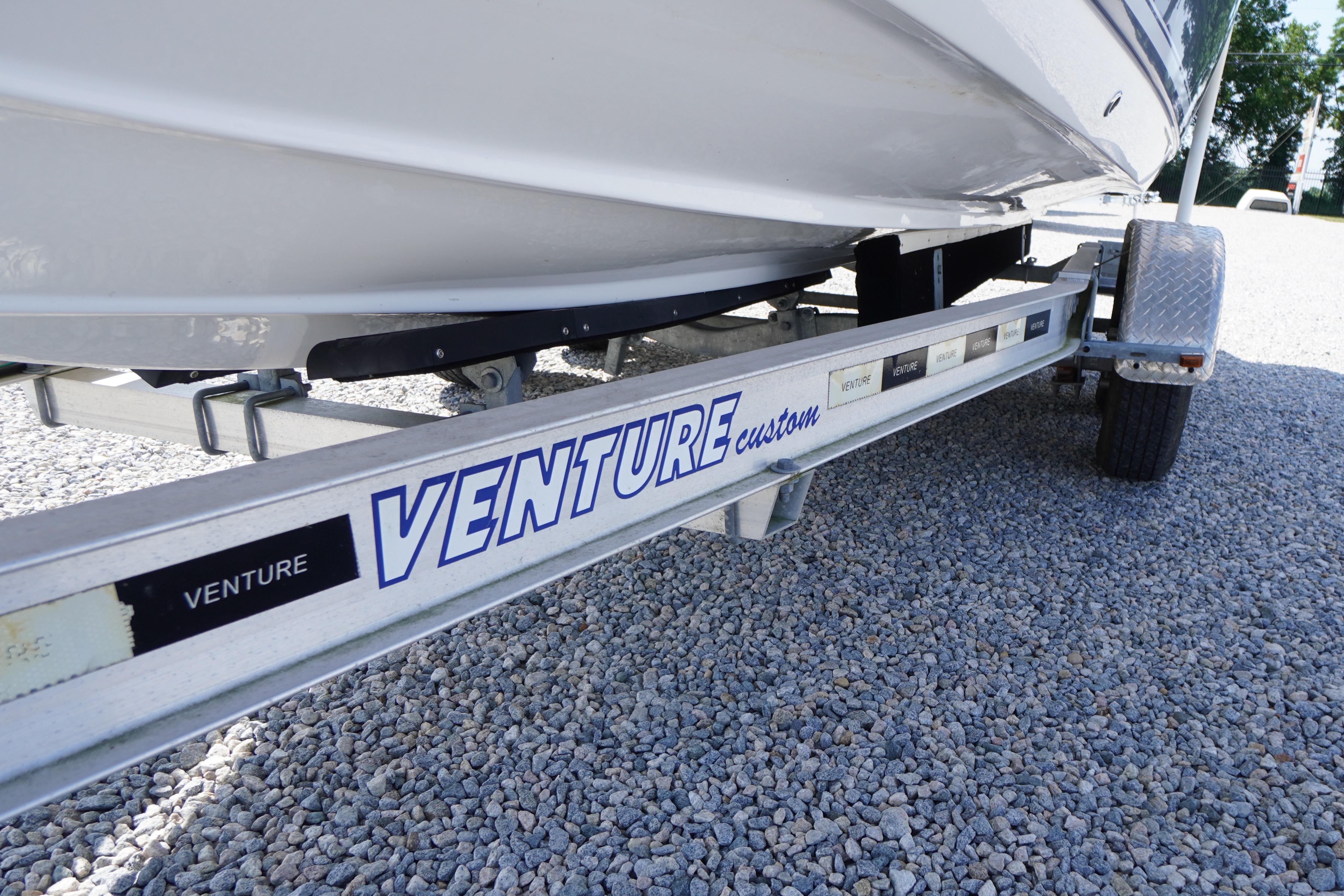 Trailer for 2026 Tidewater 220 CC Adventure boat on gravel surface.