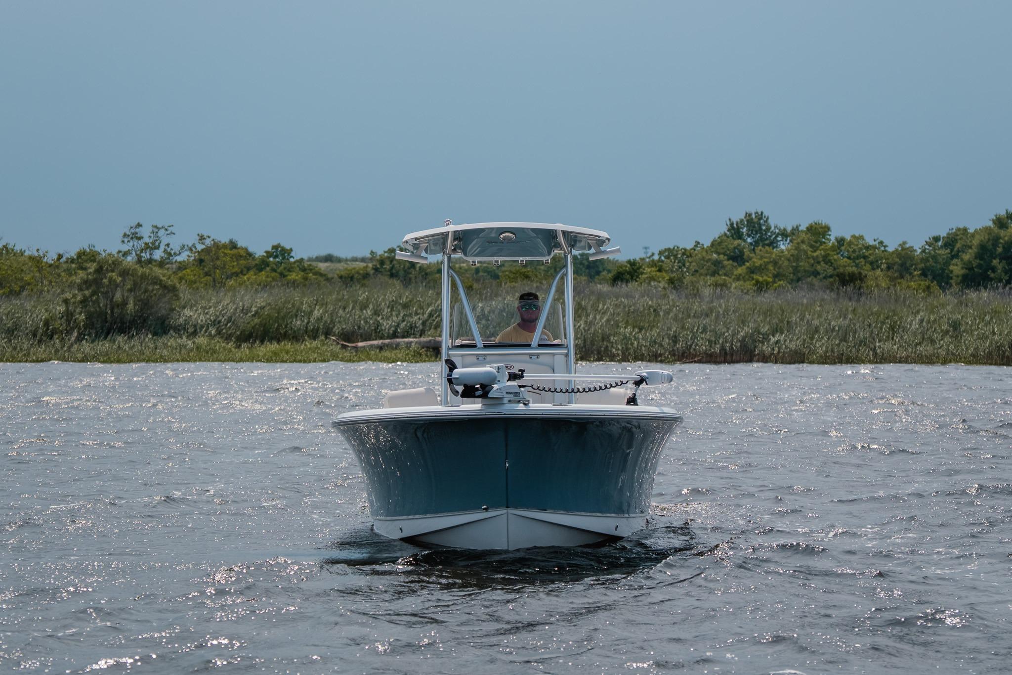 2022 Sea Hunt Ultra 229 boat cruising on a calm lake with lush greenery.