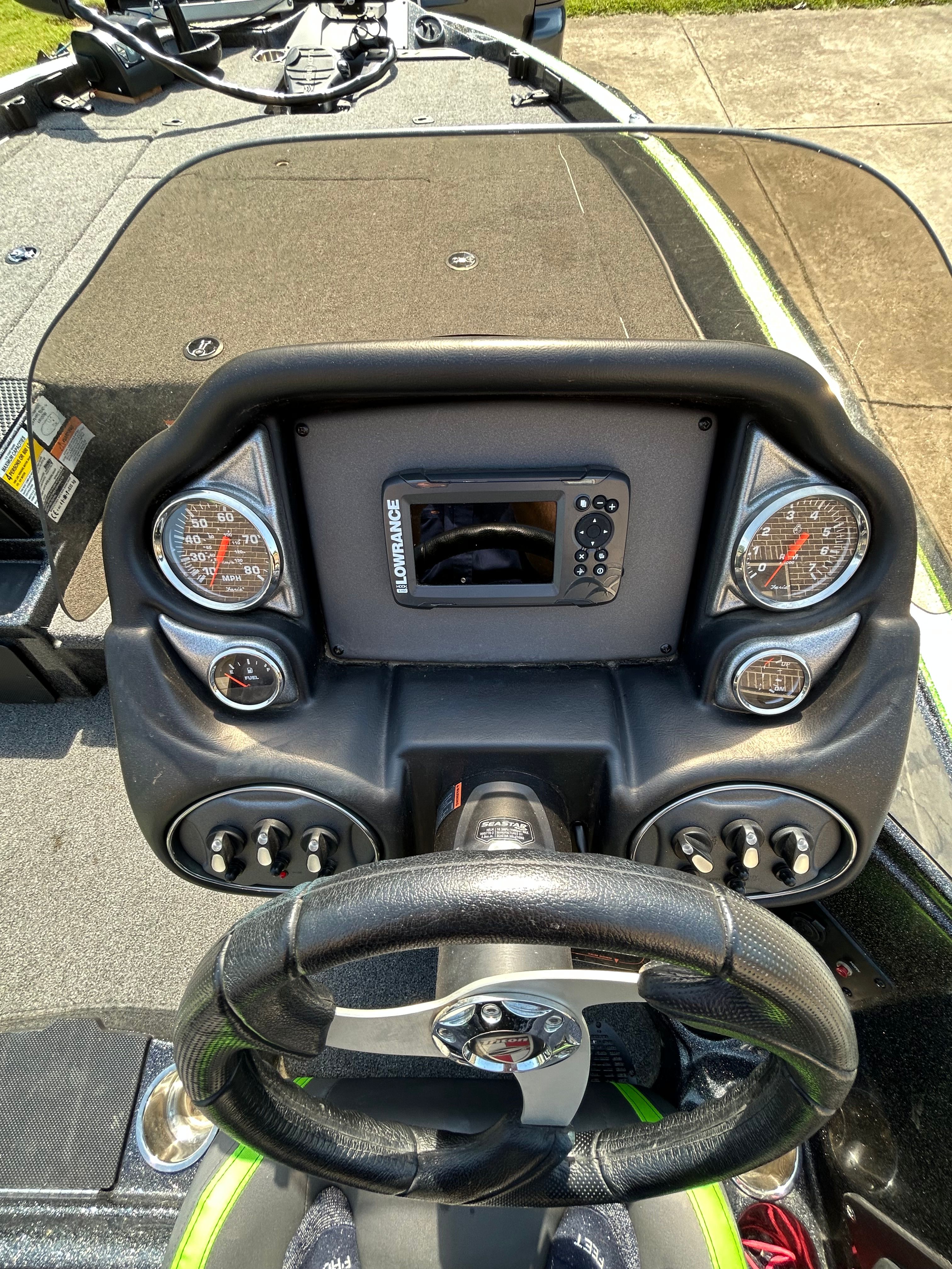 The image shows the cockpit of a Trident 189 TRX boat with steering and instruments.