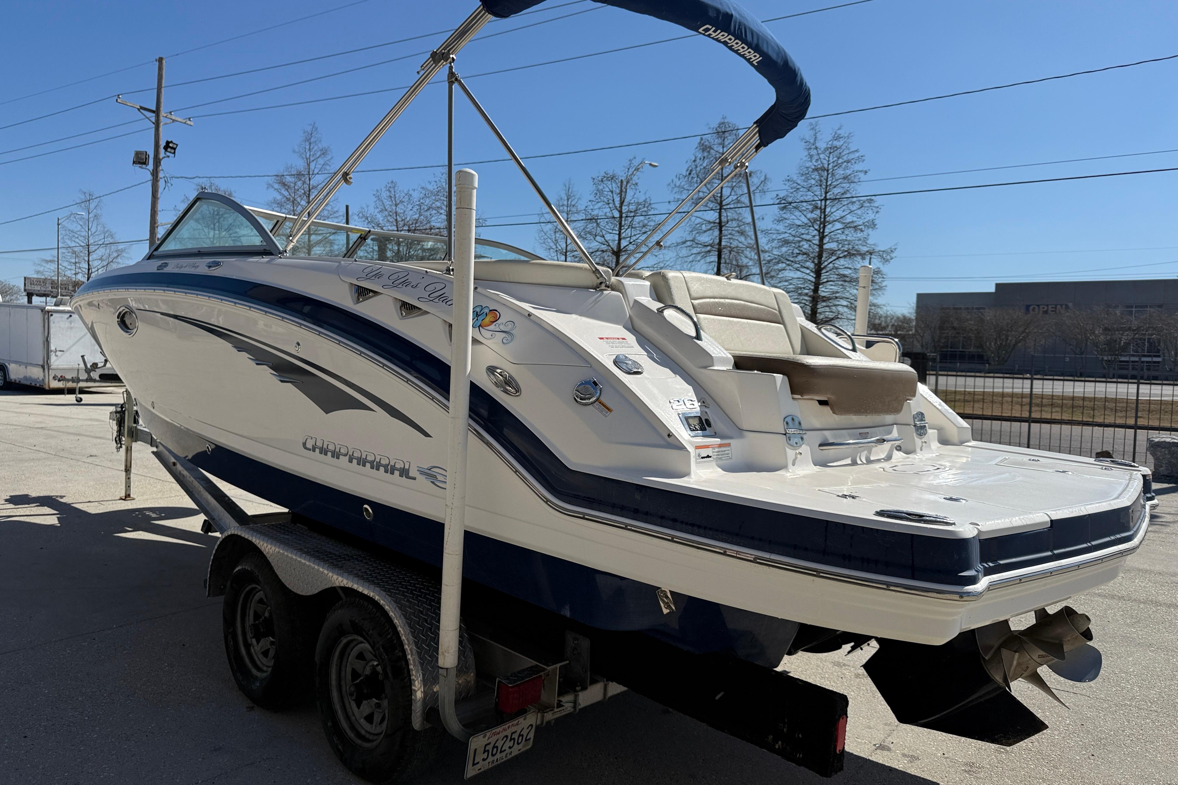 2014 Chaparral 264 Sunesta boat on trailer, parked outdoors under clear blue sky.