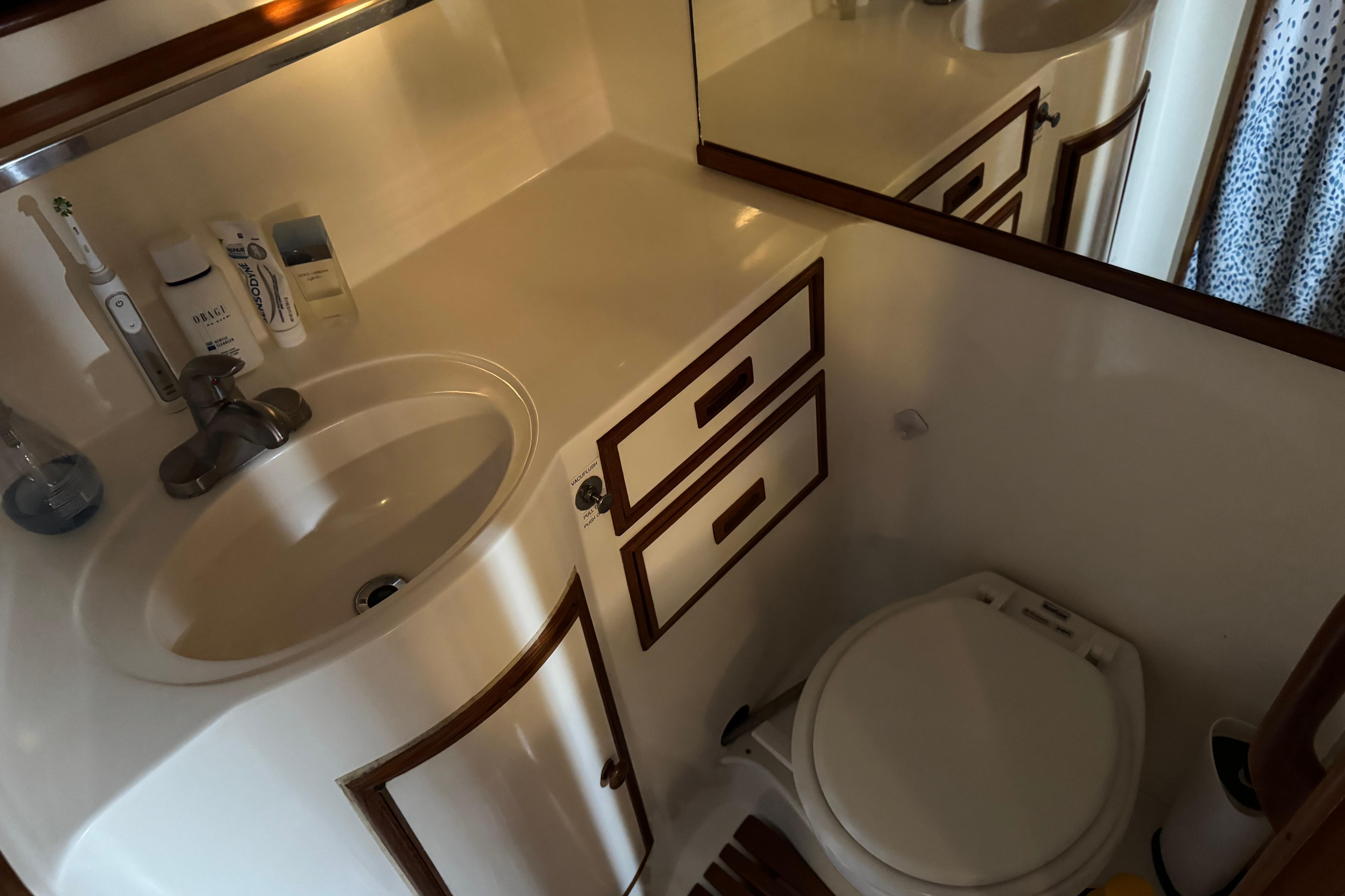 Compact bathroom in a 1987 President 37 yacht, featuring sink, mirror, and toilet.