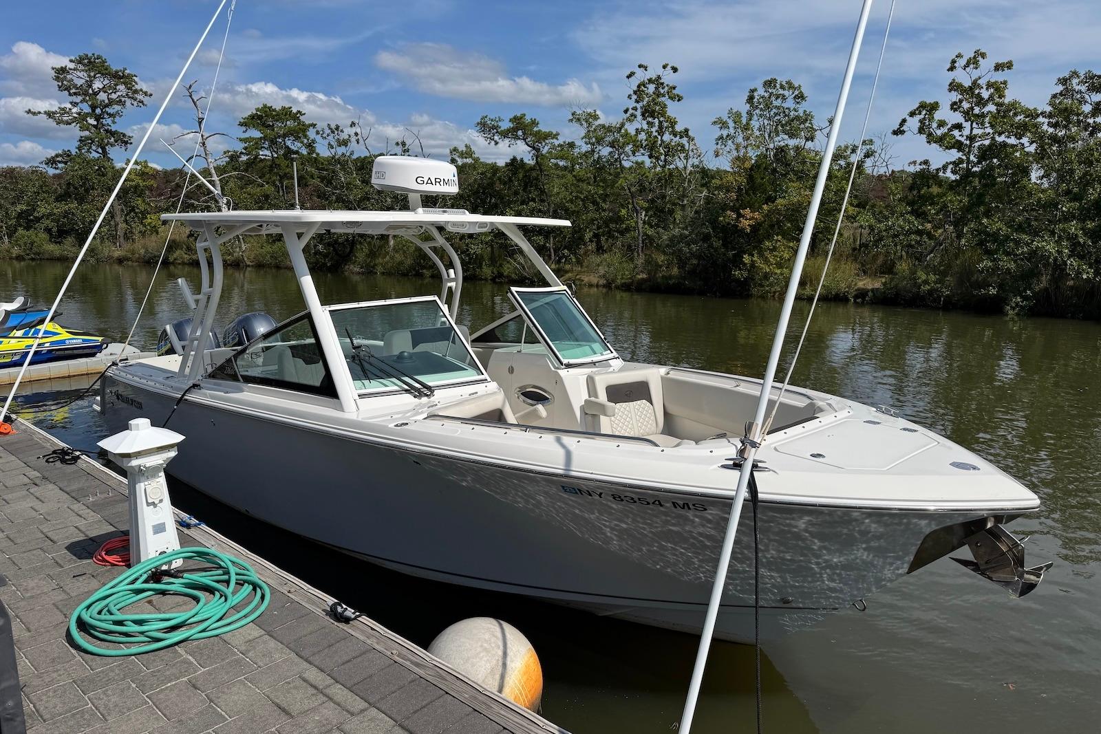 2022 Sailfish 276 DC boat docked by a serene riverbank.