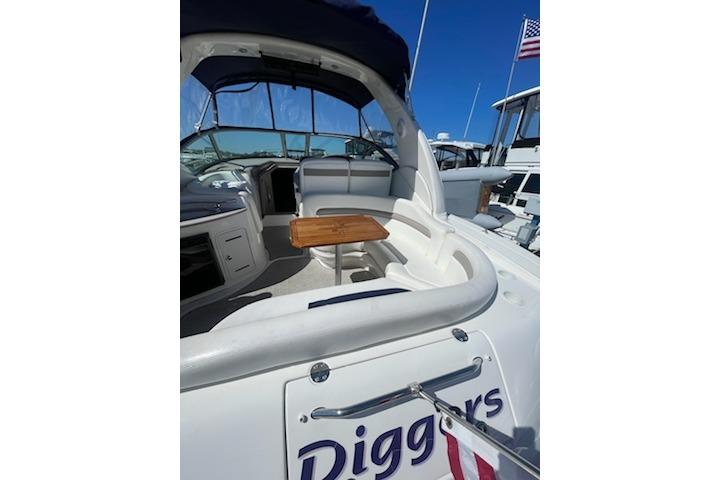 2005 Sea Ray Sundancer 320 yacht interior with seating and table, docked under clear blue sky.
