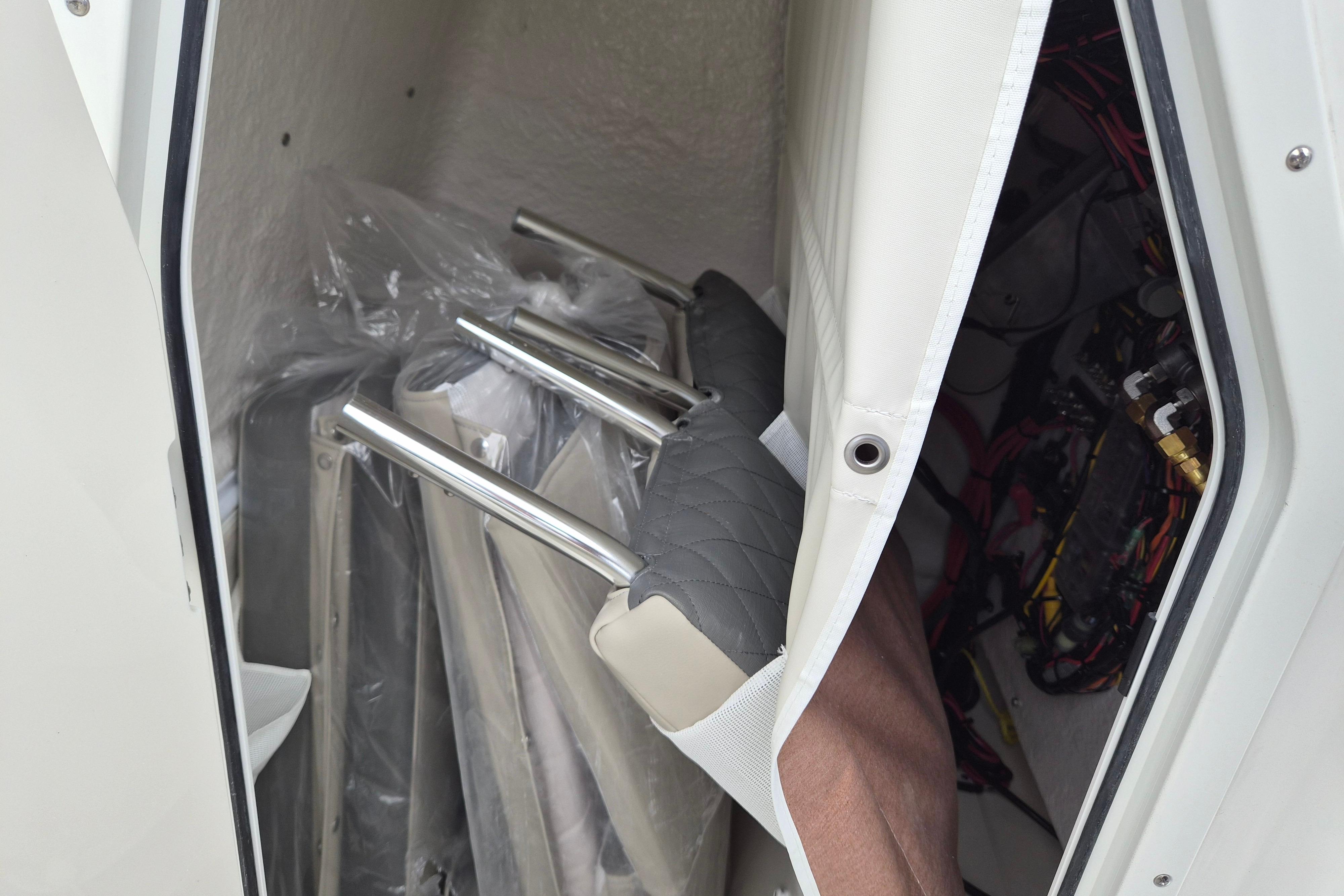 Storage compartment in a 2026 Key West 219 FS boat with seat cushions and metal frames.