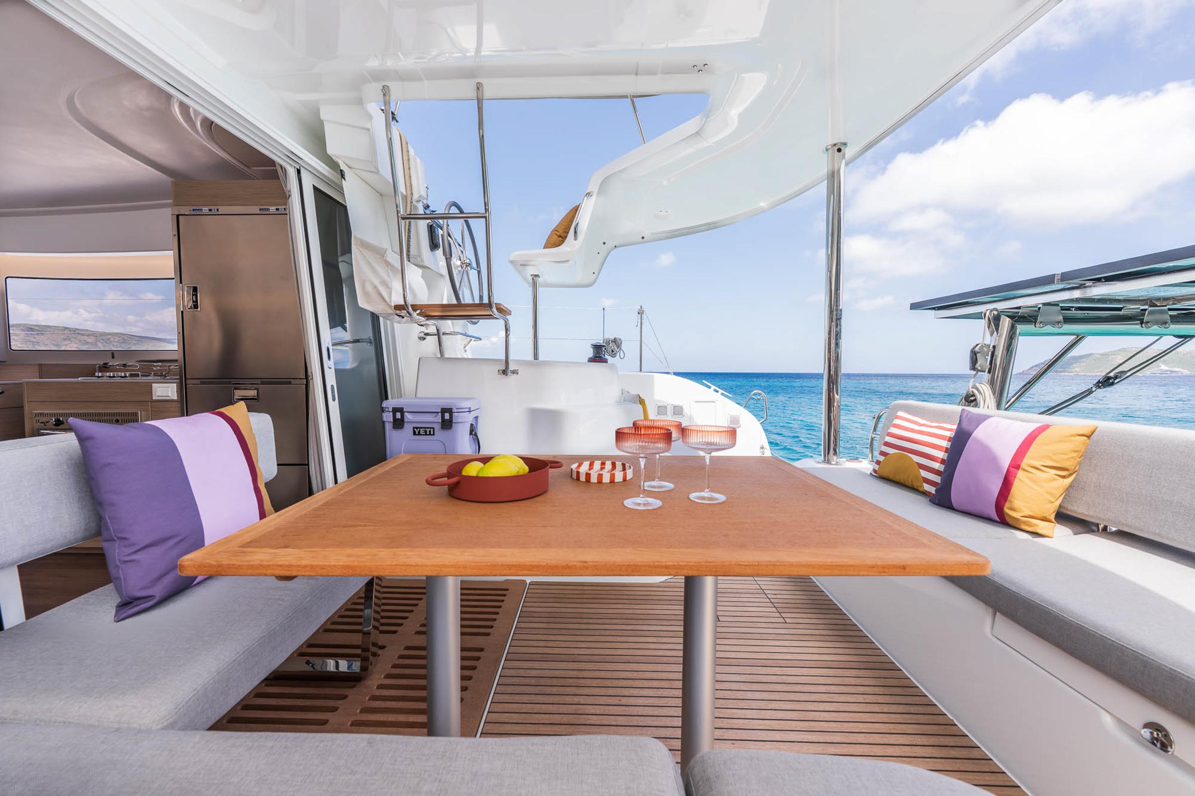 Luxurious Lagoon 38 yacht interior with dining area, colorful cushions, and ocean view, 2025 model.