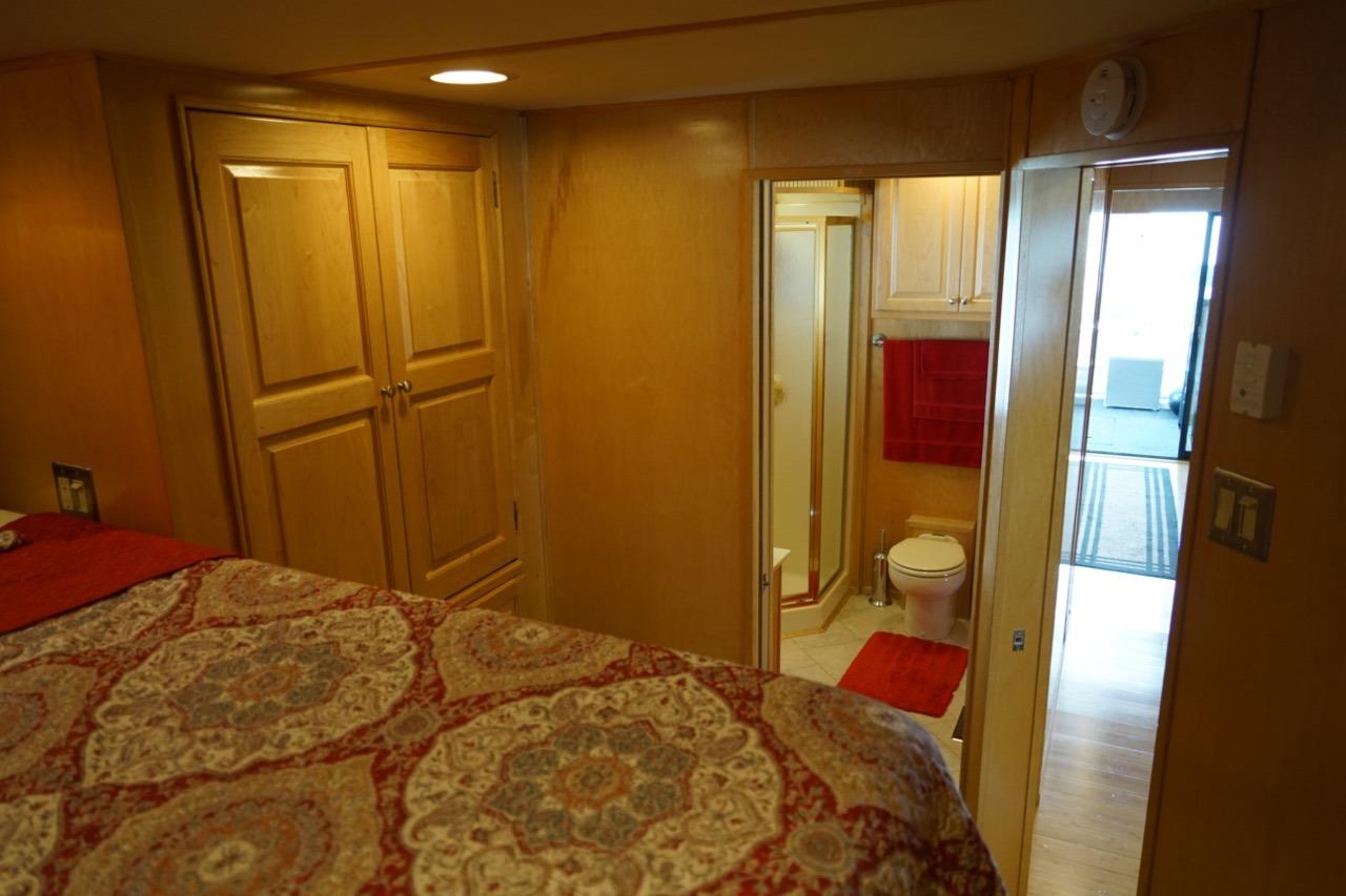 Interior of 2000 Stardust Cruisers houseboat with bedroom, bathroom, and wooden cabinetry.