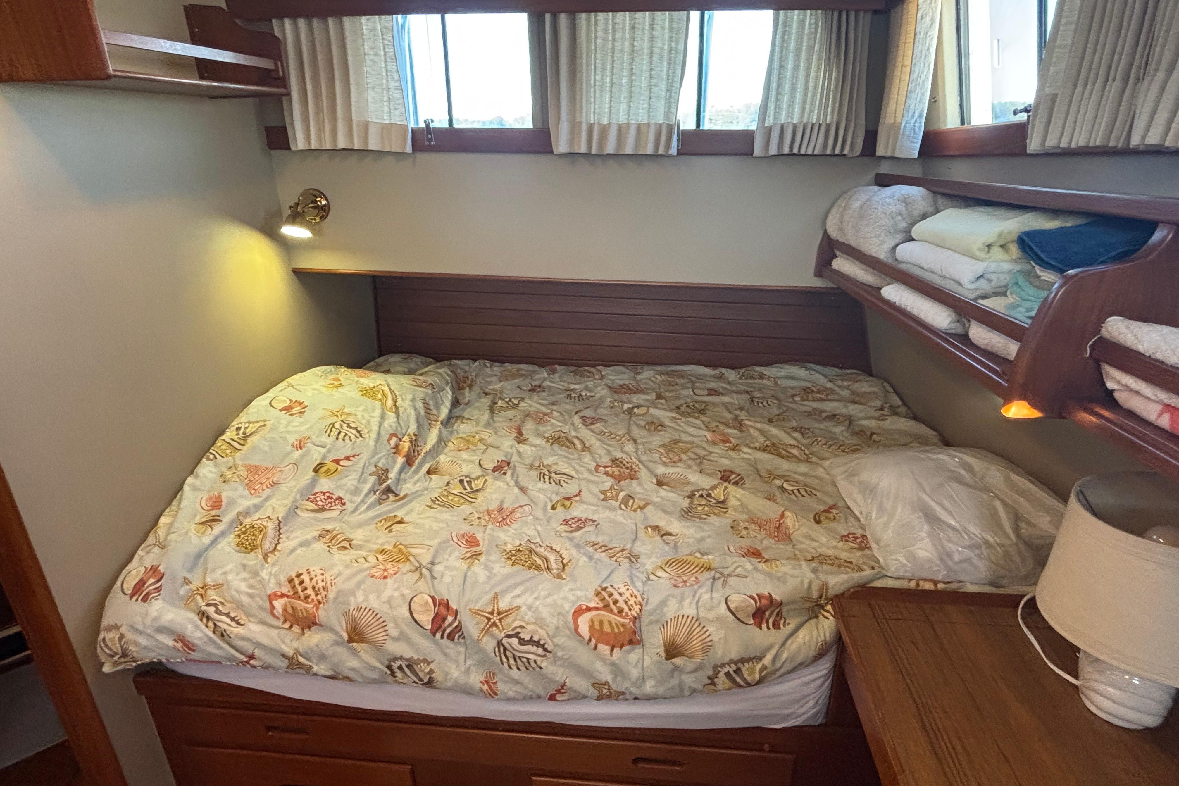 Cozy bedroom in 1989 Grand Banks 46 Classic yacht with seashell-themed bedding.