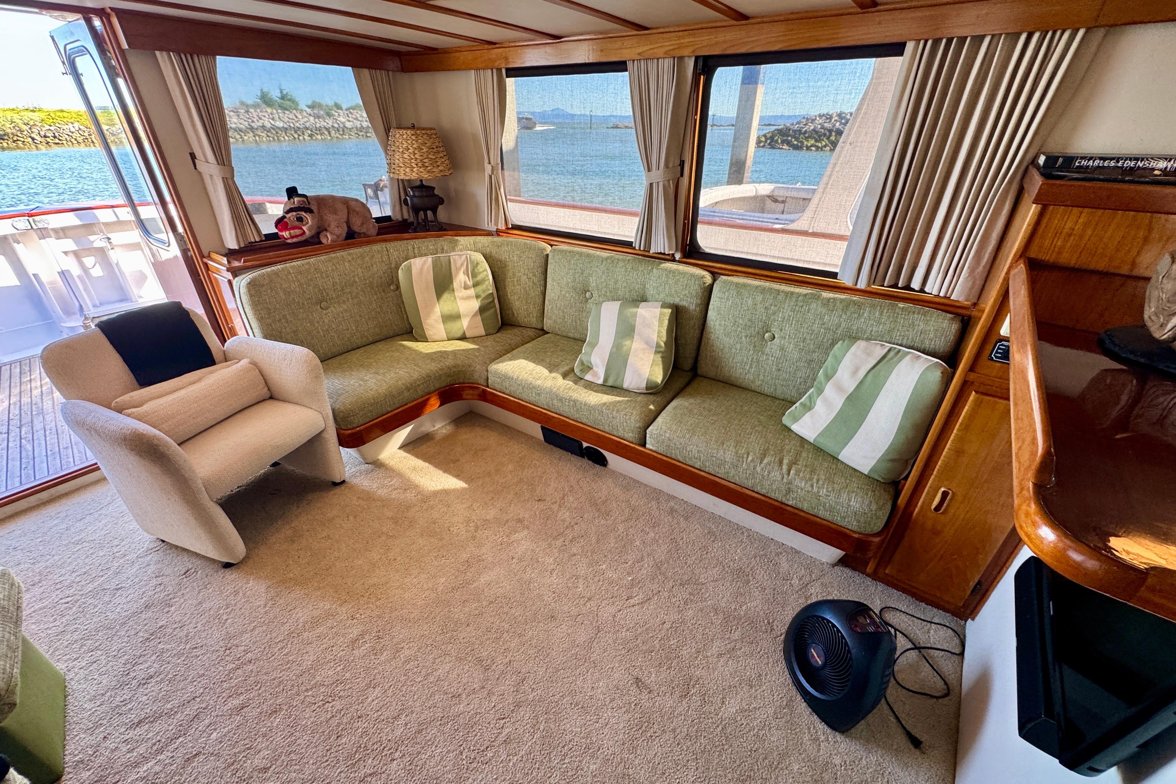 Interior of a 1958 Blanchard Pilothouse boat with cozy seating and scenic views.