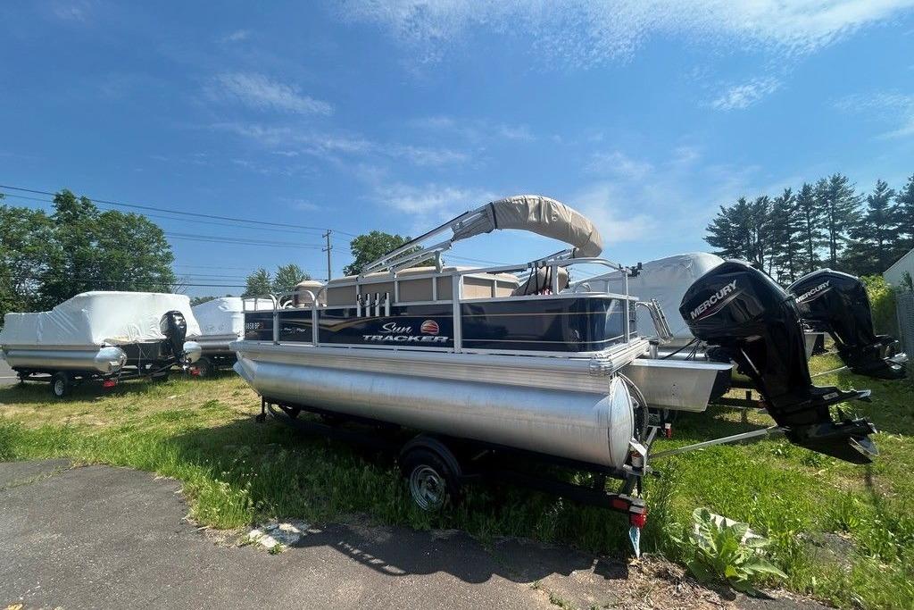 2023 Sun Tracker Bass Buggy 18 DLX pontoon boat with Mercury engines, parked outdoors.