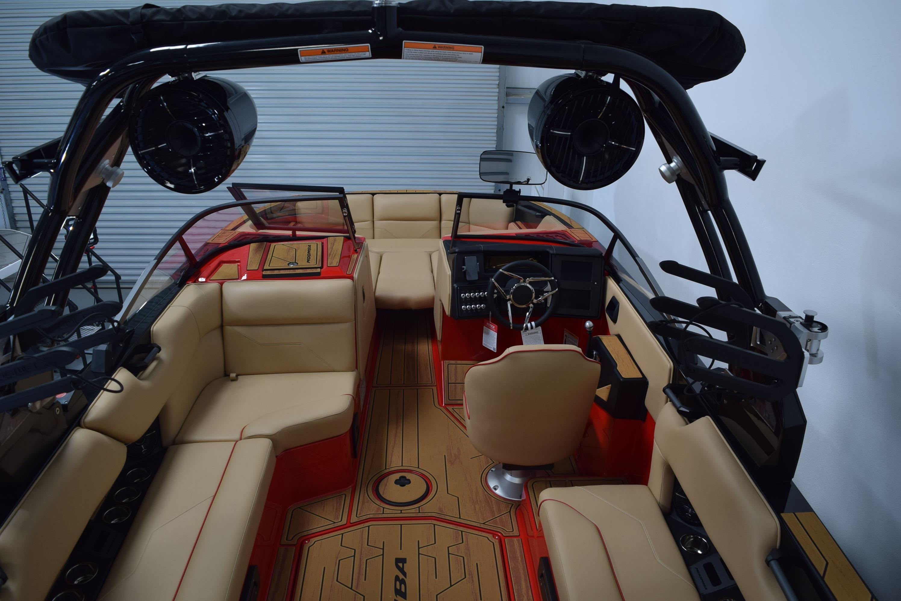 2026 Moomba Max boat interior with beige seating, red accents, and advanced dashboard.
