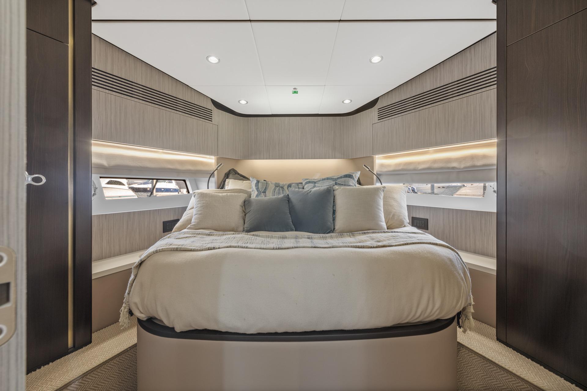 Luxurious bedroom interior of 2019 Azimut 55 yacht with modern design and cozy bedding.