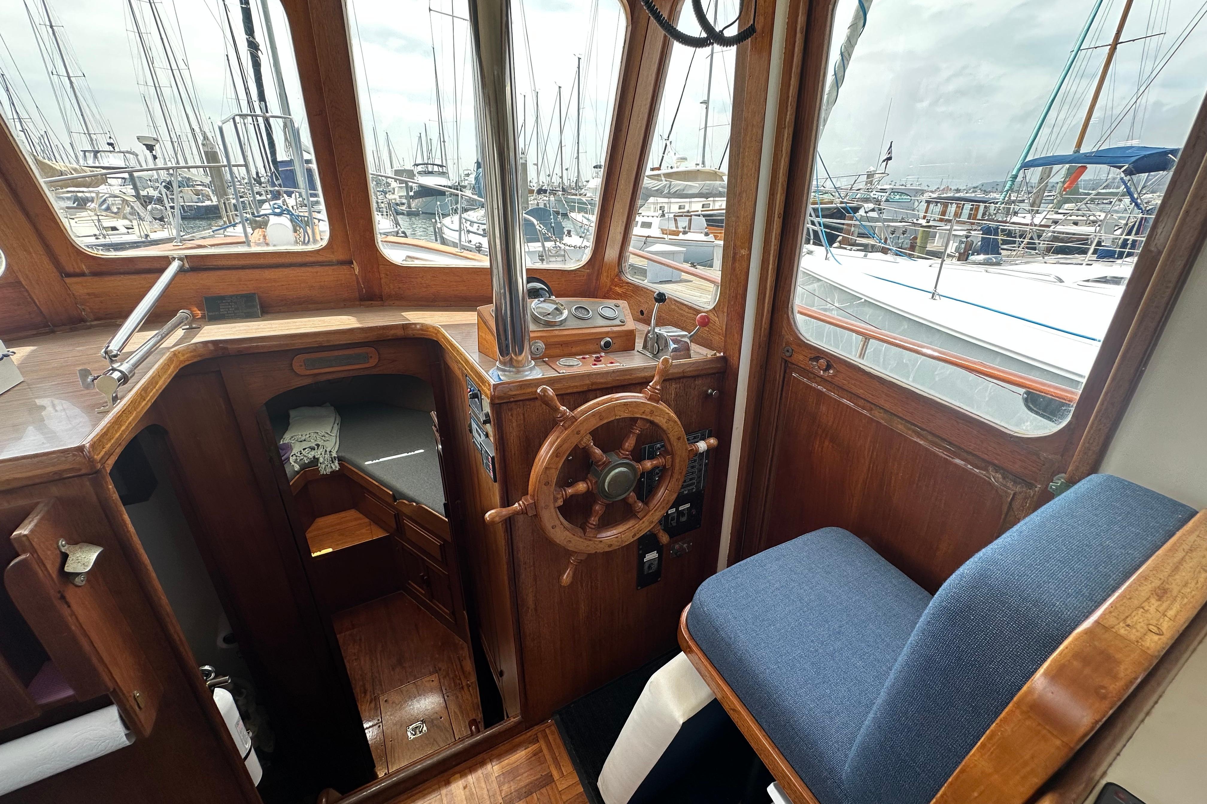Interior of a 1973 CHB 33 boat with wooden helm and marina view.