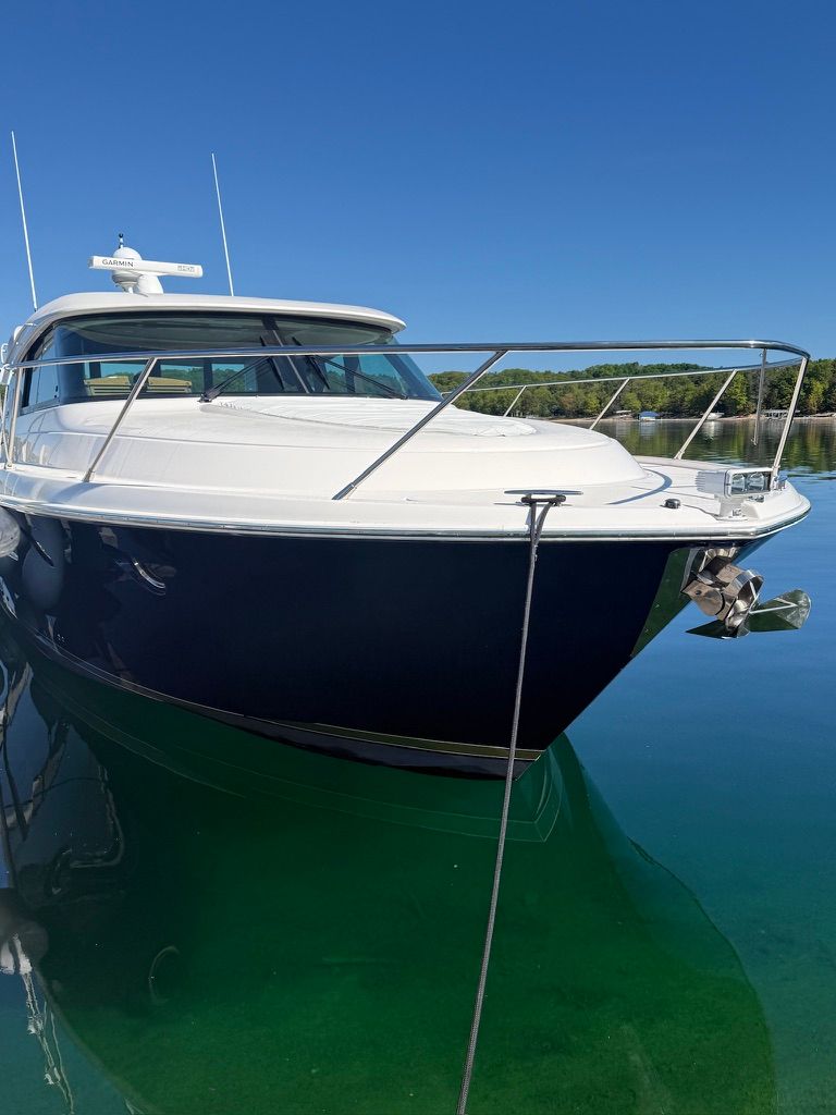 A 2017 Tiara Yachts C44 Coupe is anchored on clear water, showcasing its sleek design.