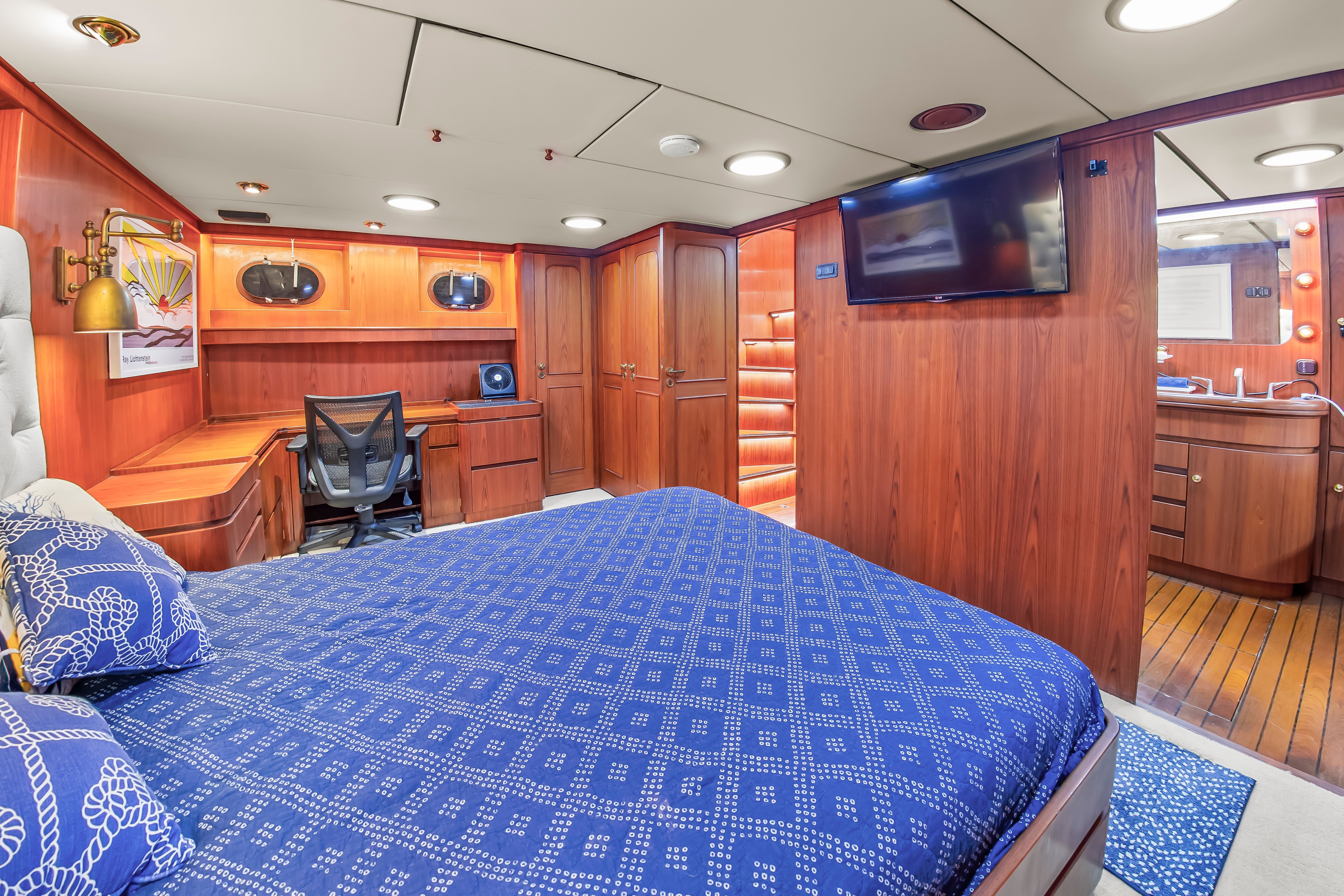 Luxurious cabin with double bed, wooden furniture, and desk on a Jongert 78 Motor Yacht.