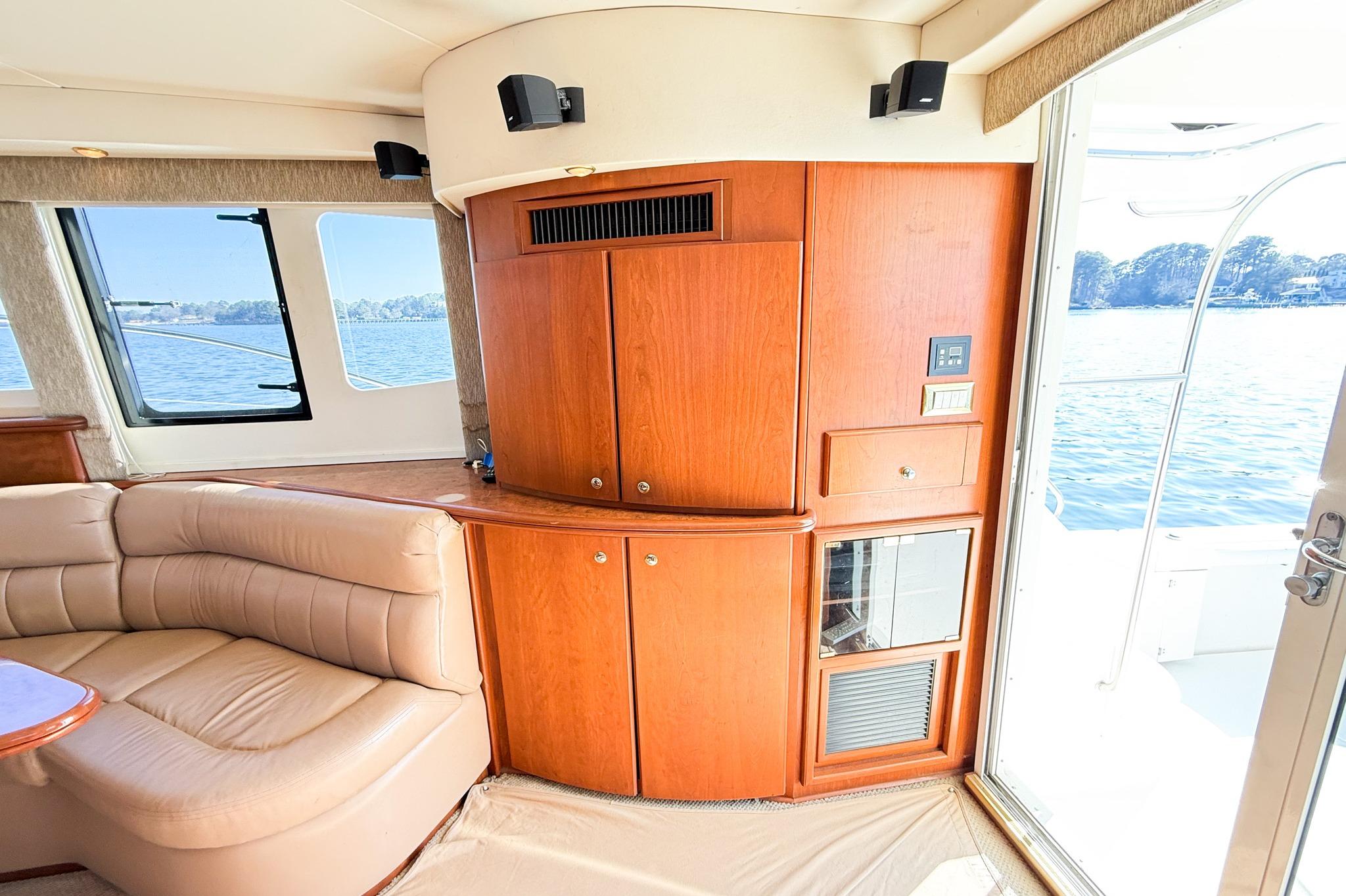 Interior of 2004 Silverton 48 Convertible yacht with wood cabinetry and leather seating by a window.