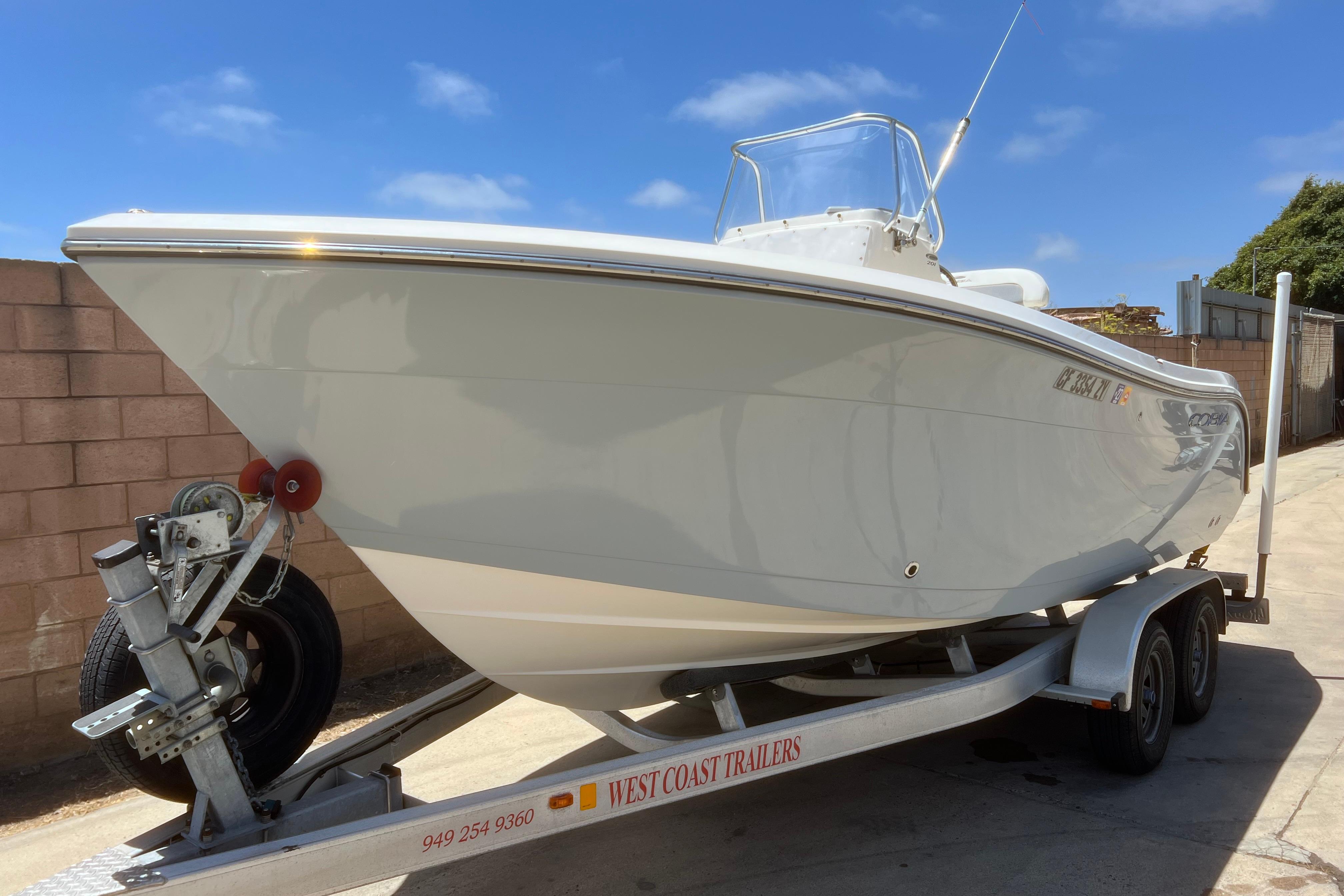 2018 Cobia 201 Center Console boat on trailer, parked outdoors under clear blue sky.