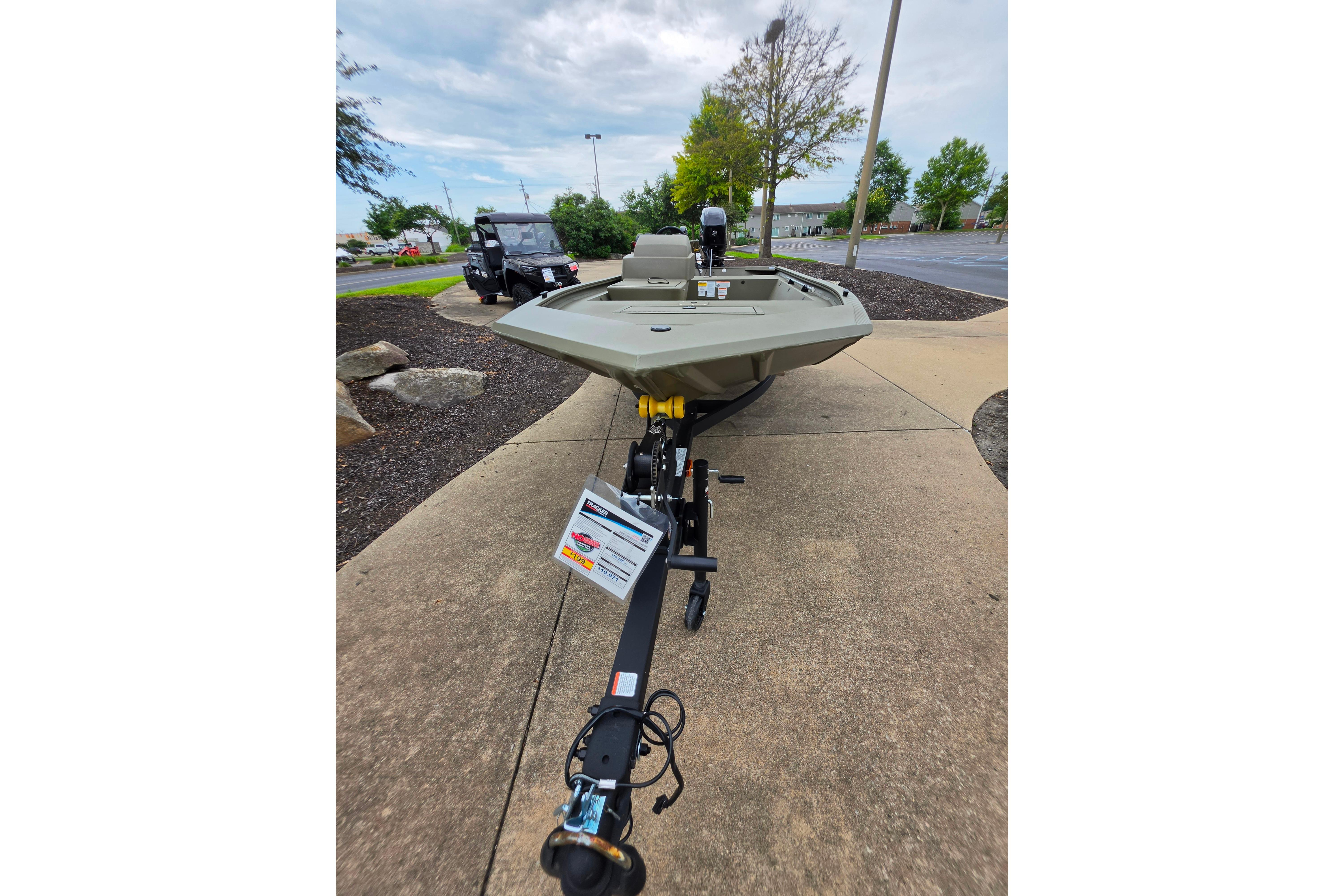 2026 Tracker Grizzly 1648 SC boat on trailer, parked outdoors on a concrete path.