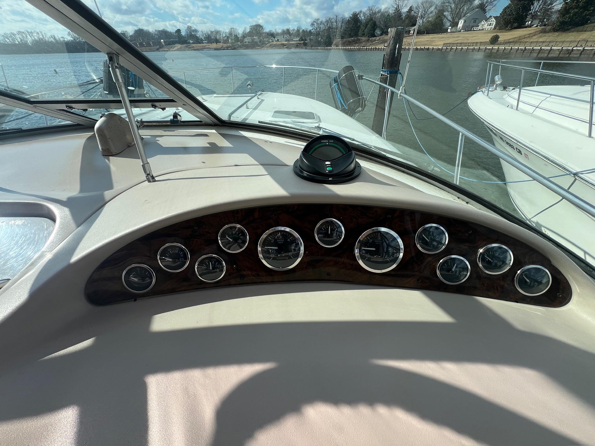 2001 Sea Ray 340 Sundancer dashboard with gauges, docked on a sunny day.