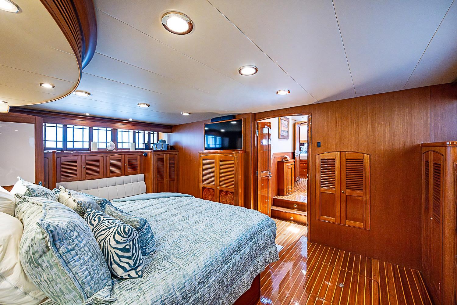 Luxurious bedroom interior on 2014 Marlow 80 Explorer yacht with elegant wood finishes.