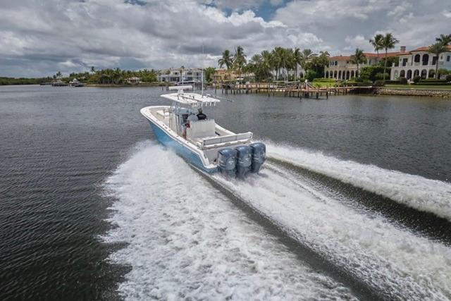 2015 Invincible 36 boat cruising on a scenic waterway with waterfront homes.