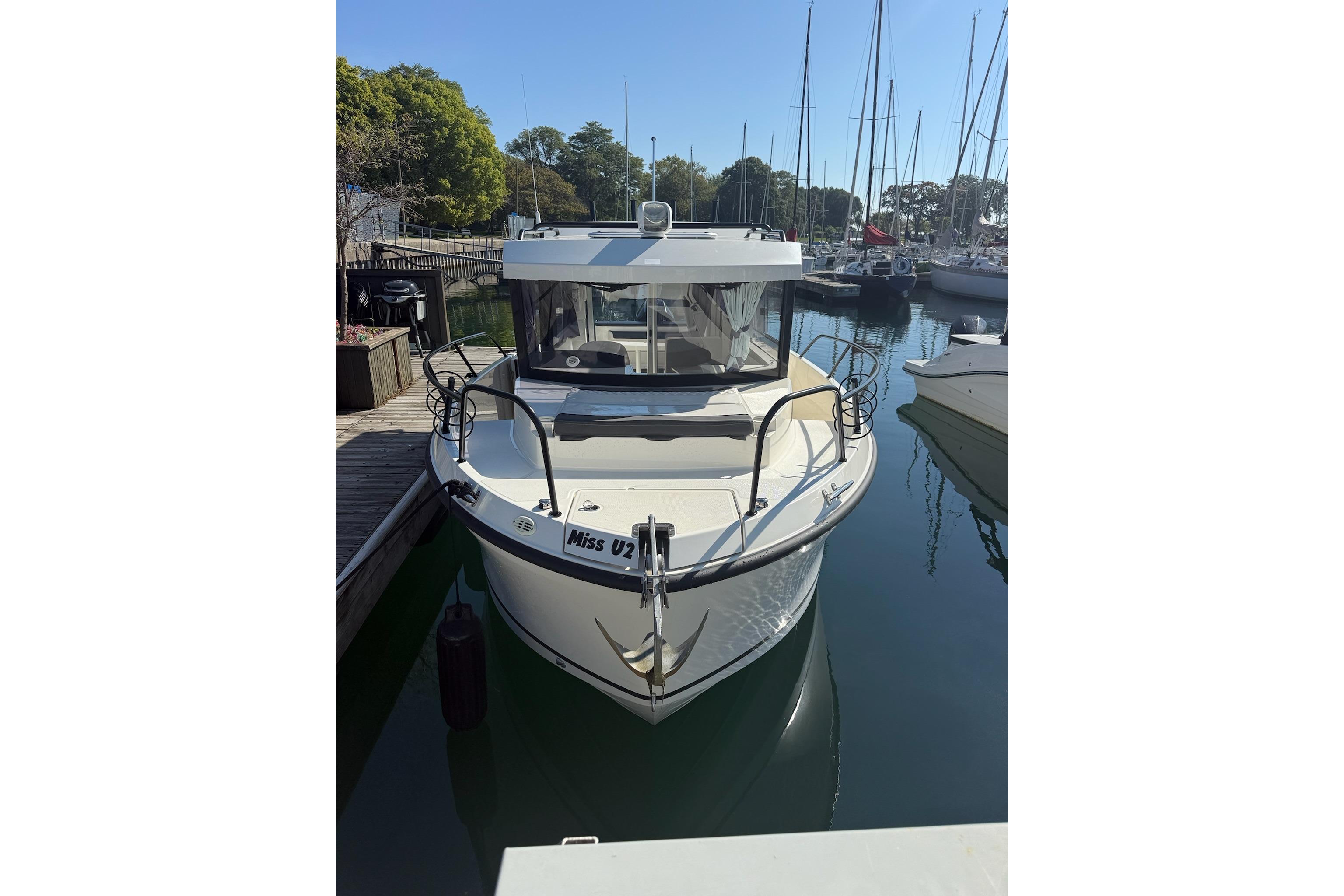 2024 Bayliner Trophy T25 Pilothouse docked in a marina, surrounded by sailboats.