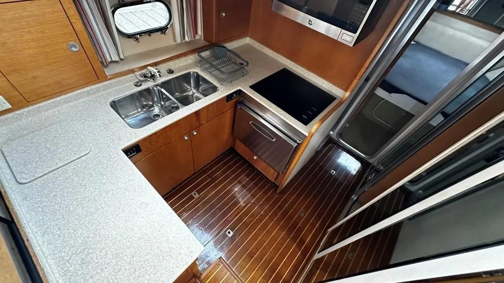 Interior of 1985 Princess Sedan Flybridge yacht kitchen with wood flooring and modern appliances.