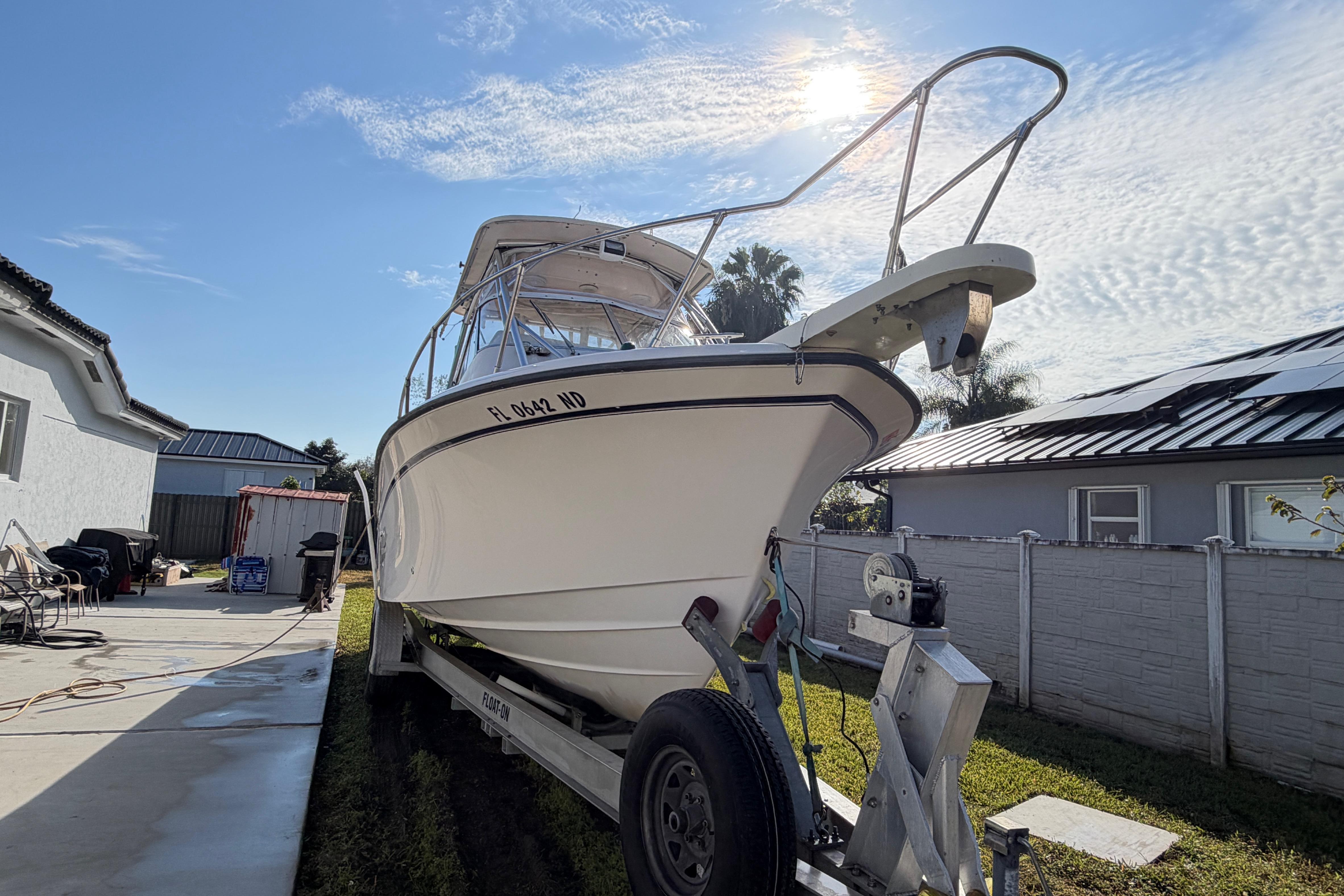 2006 Grady-White Sailfish 282 boat on trailer in residential driveway under sunny sky.
