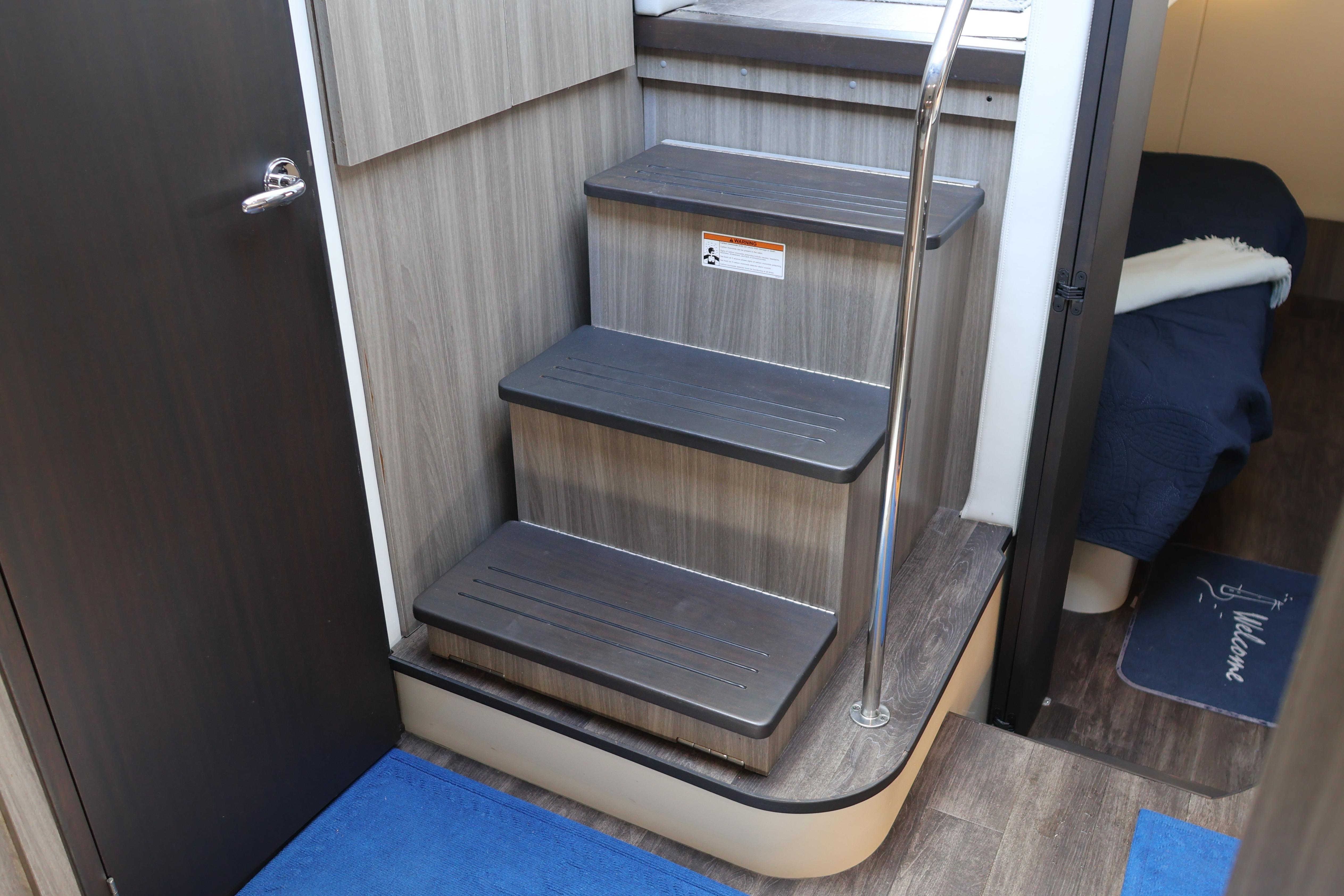 Interior stairs of 2021 Regal 42 XO yacht, featuring sleek wood design and metal railing.