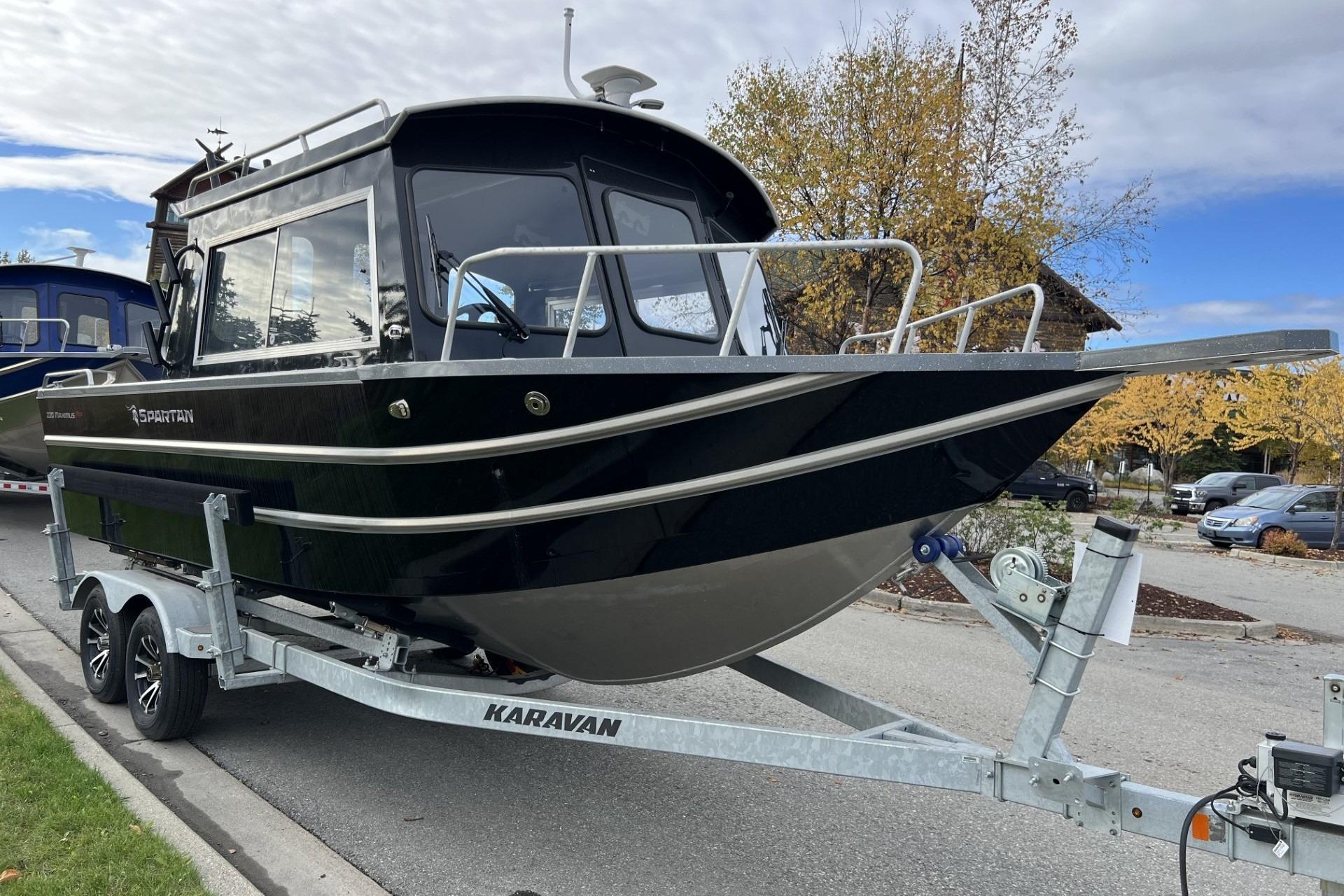 2024 Spartan 220 Maximus boat on trailer, parked on street with autumn trees.