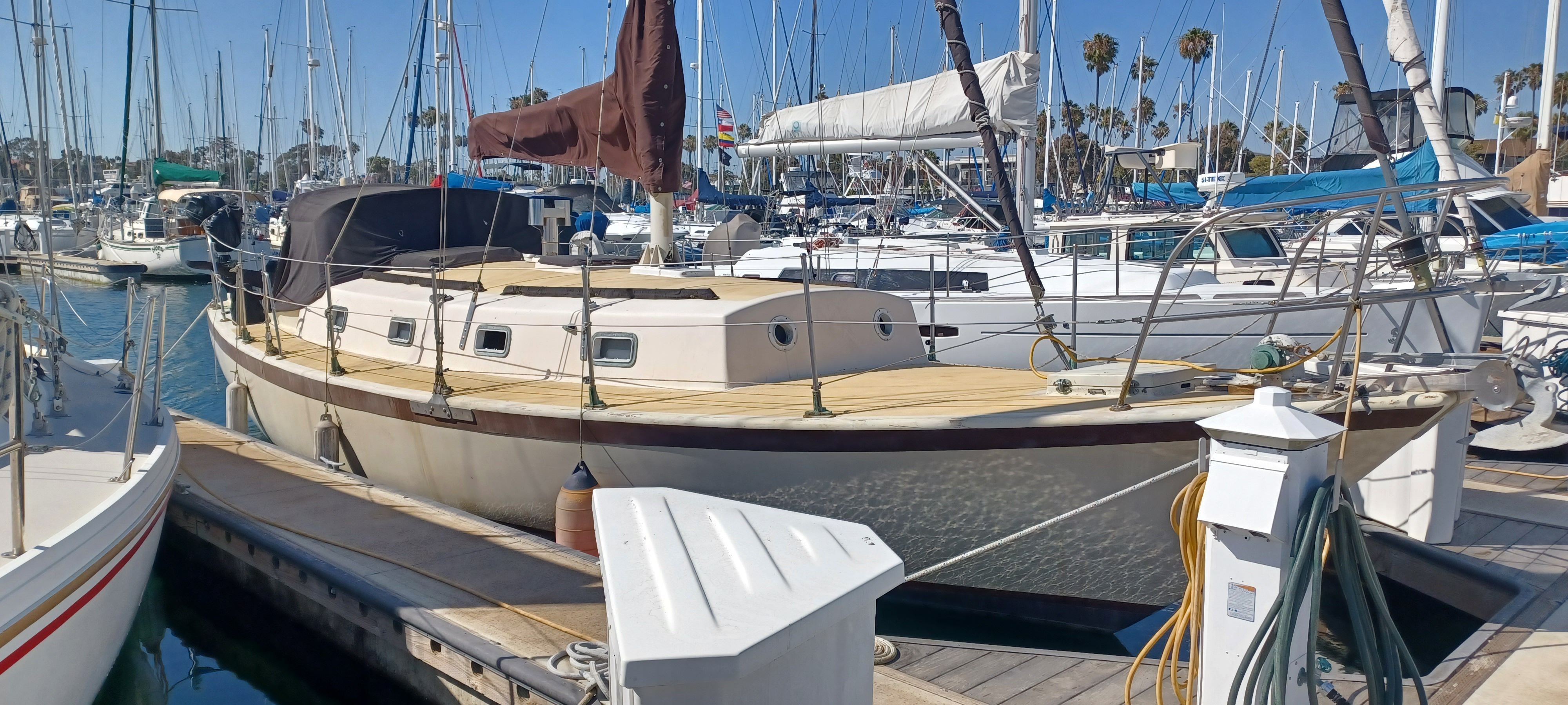 A sailboat is docked in a busy marina, surrounded by other boats.
