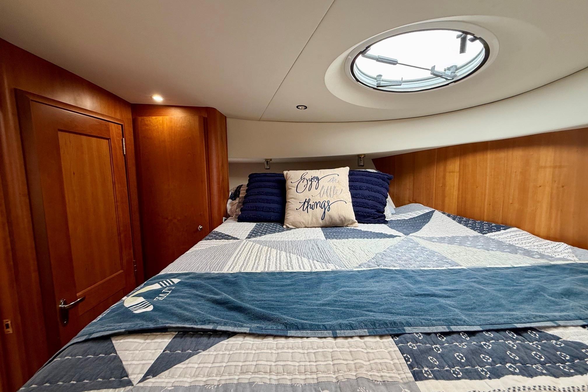 Cozy bedroom in 2004 Silverton 39 Motor Yacht with quilted bedding and porthole window.