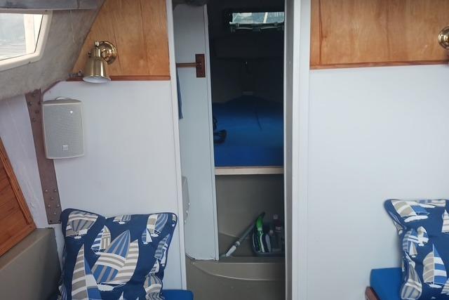 Interior of 1989 O'Day 272 sailboat with nautical-themed cushions and cozy cabin space.