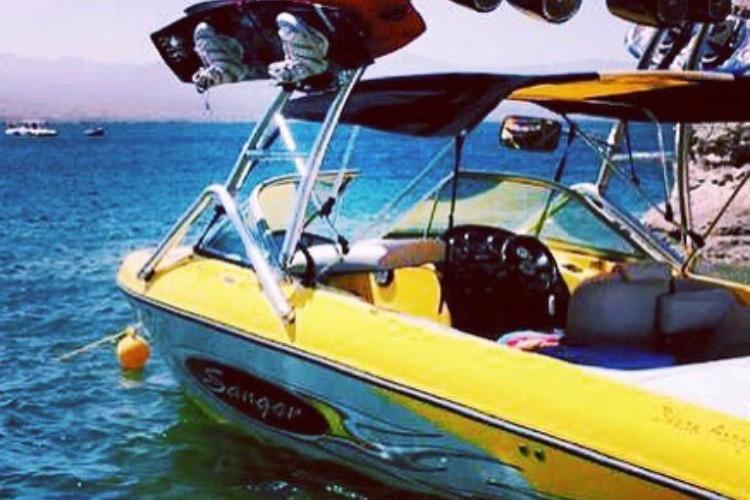 Yellow 2006 Sanger V230 boat on water, featuring wakeboard tower and vibrant design.