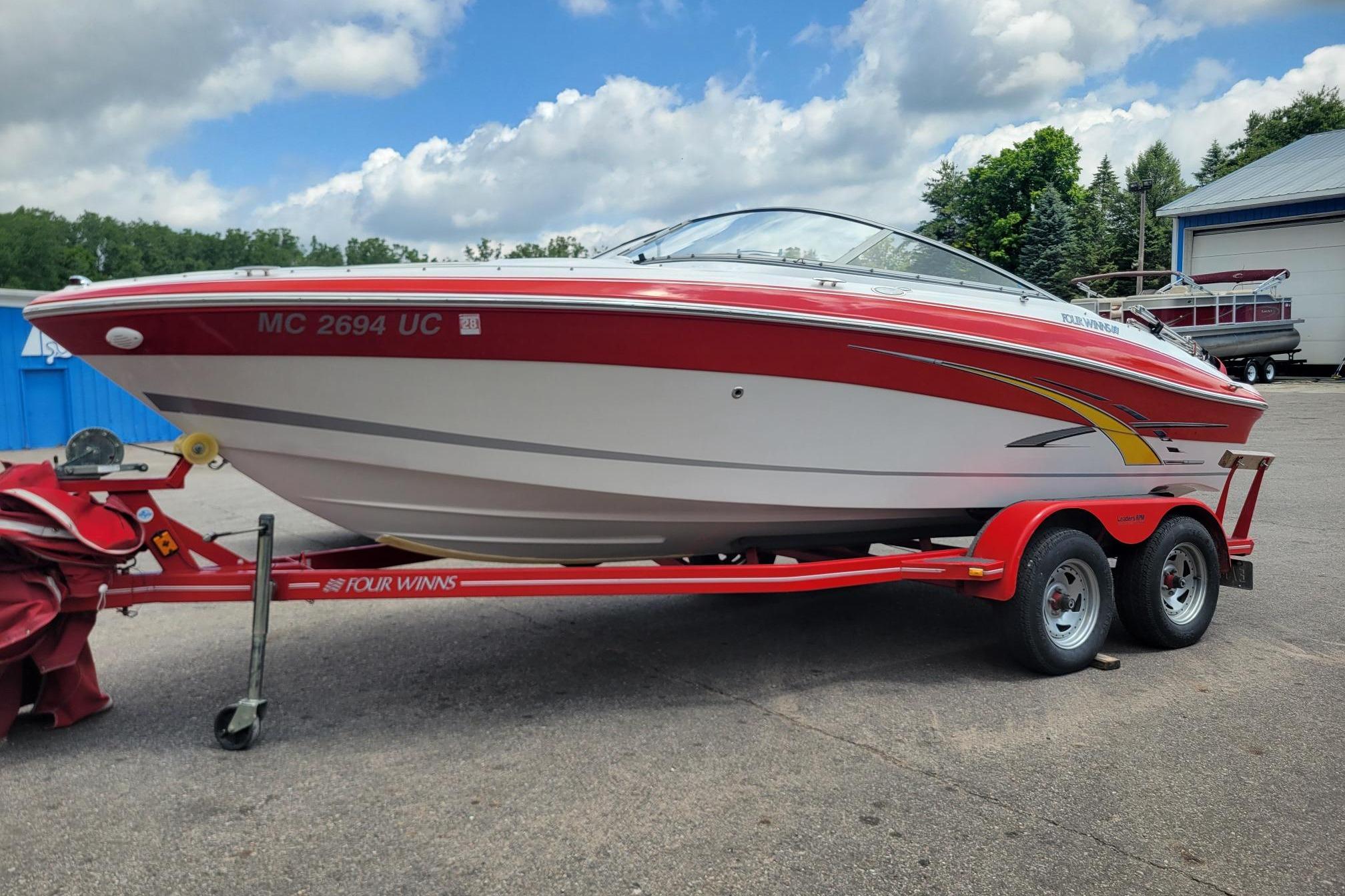2007 Four Winns 200 Horizon boat on a red trailer, parked outdoors under a cloudy sky.