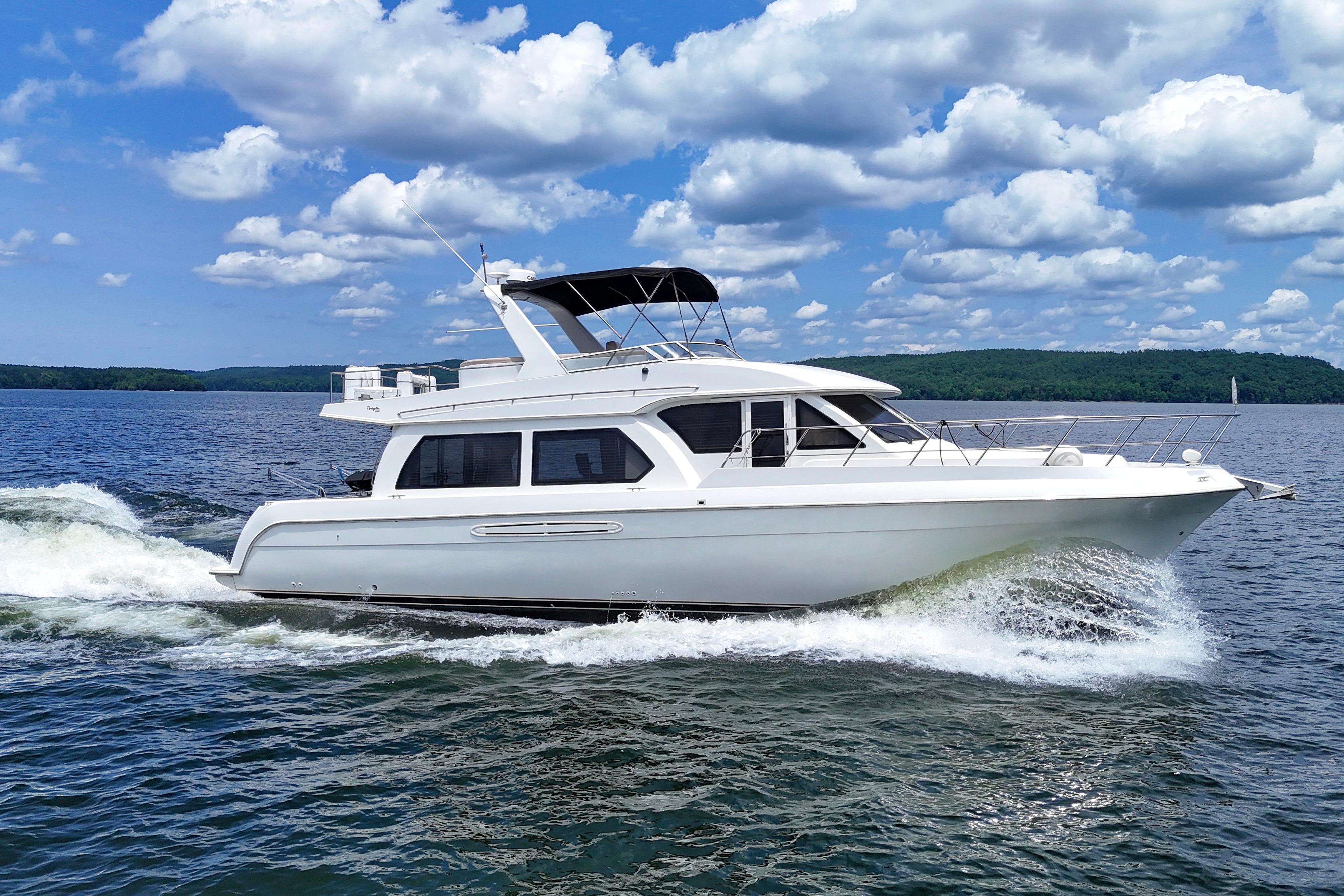 2007 Navigator 5100 yacht cruising on a lake under a blue sky with clouds.