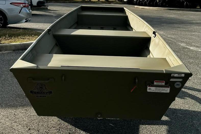 2026 Tracker Grizzly 14 Jon boat in a parking lot, showcasing its sturdy design.