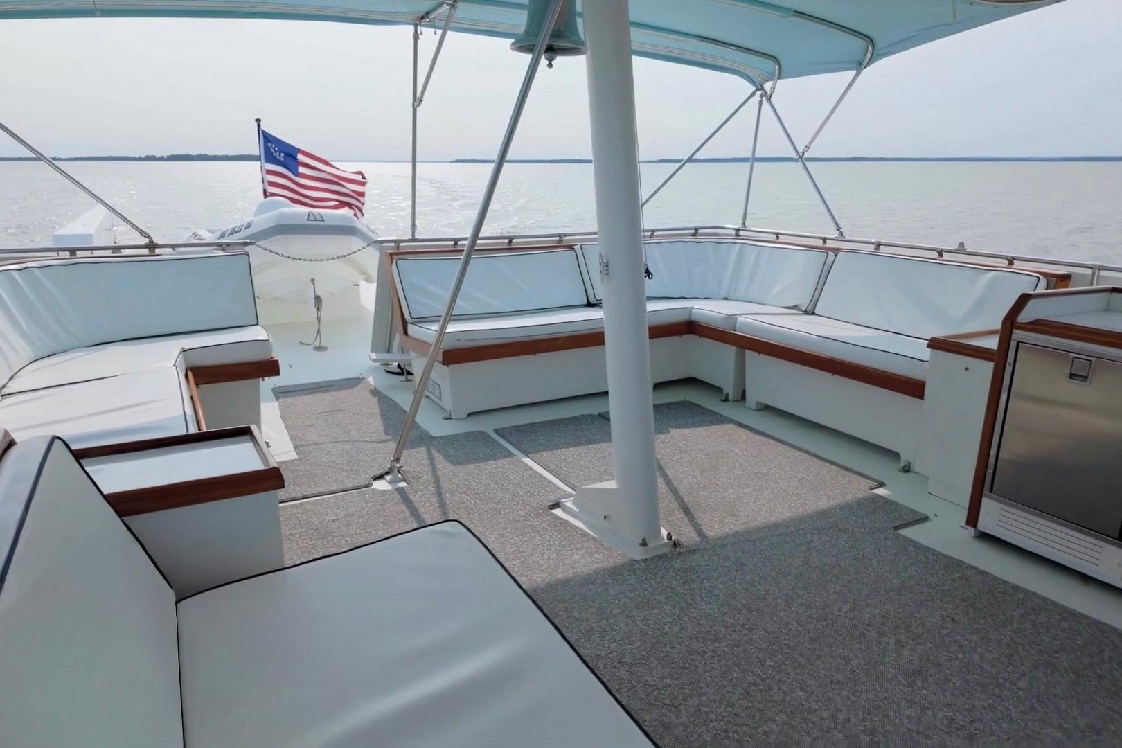 Spacious deck of 1980 Hatteras 70 Motor Yacht with seating and American flag.