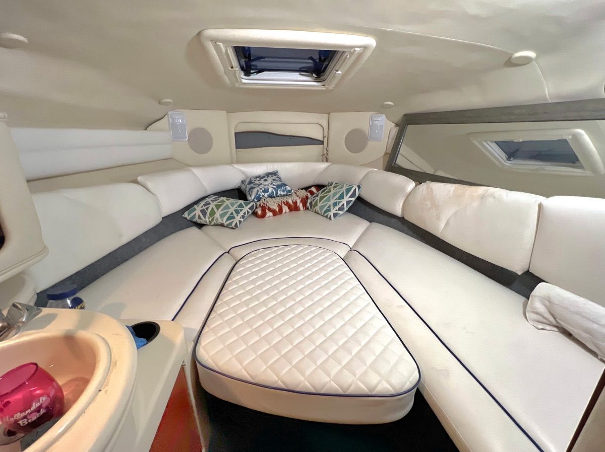 Interior of a Sea Ray Sundancer 260 with cozy white cushions and pillows.