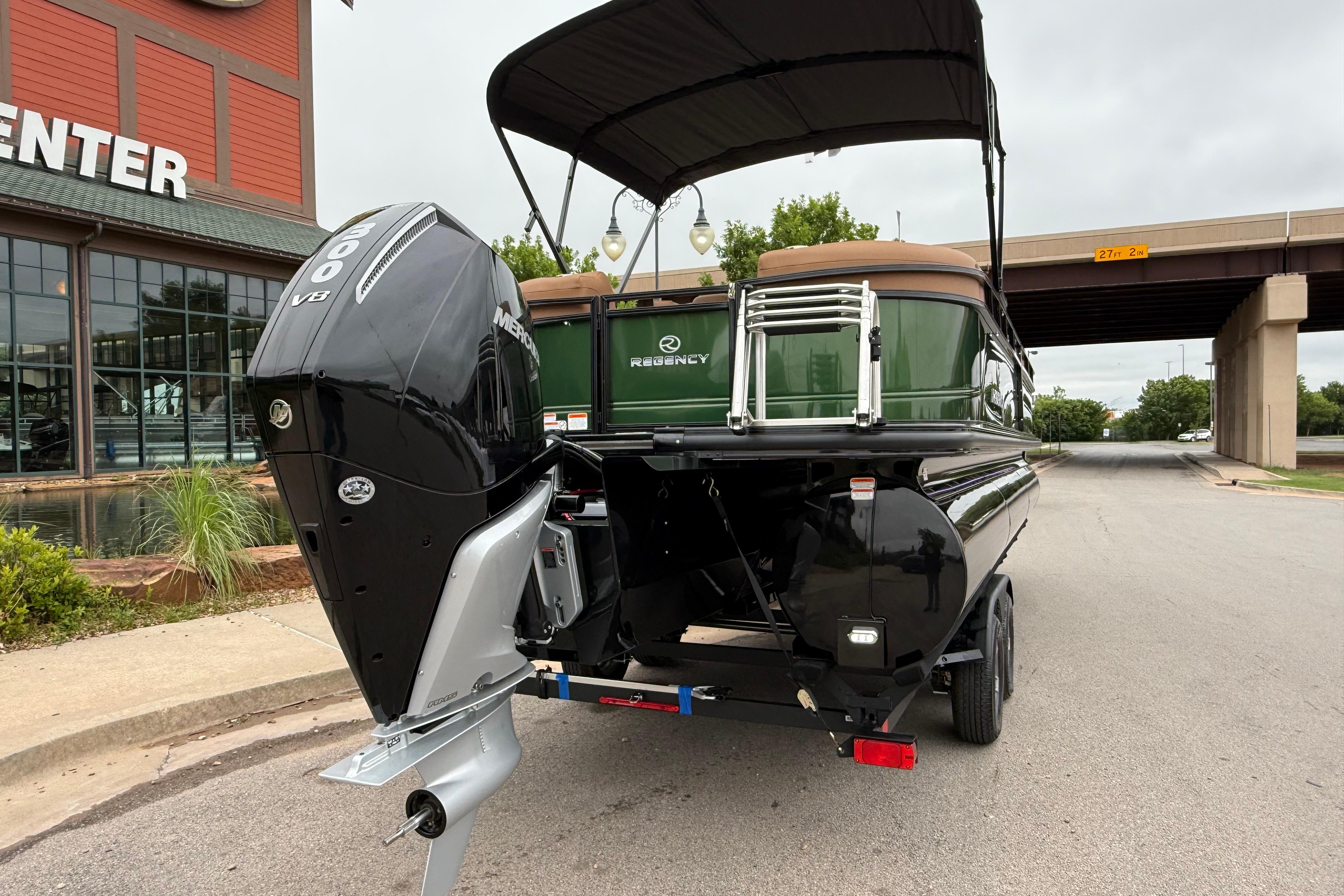 2026 Regency 250 DL boat with Mercury 600 V8 engine, parked near a building and bridge.