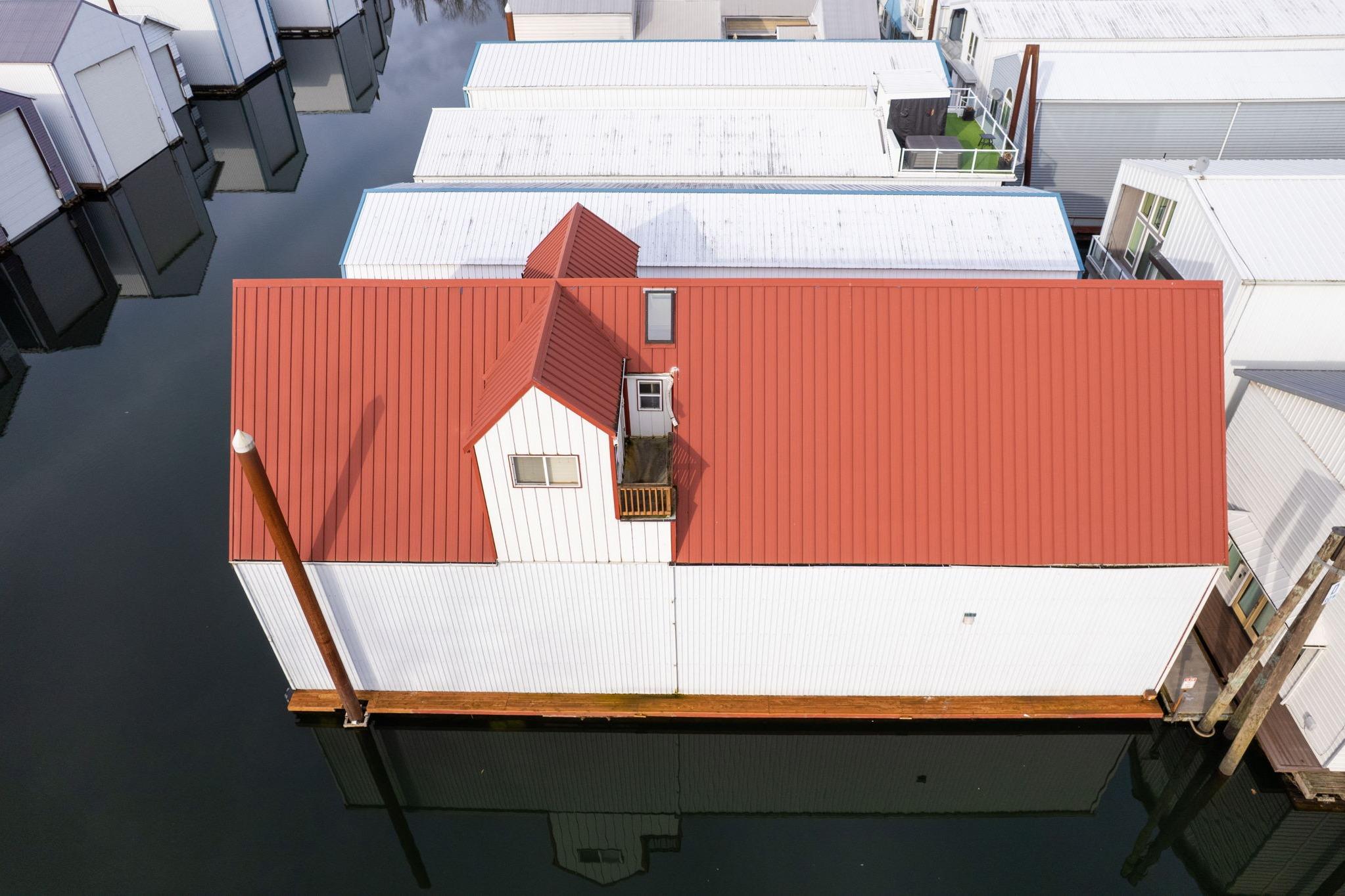 Aerial view of a 1976 custom boathouse with red roof on calm water.